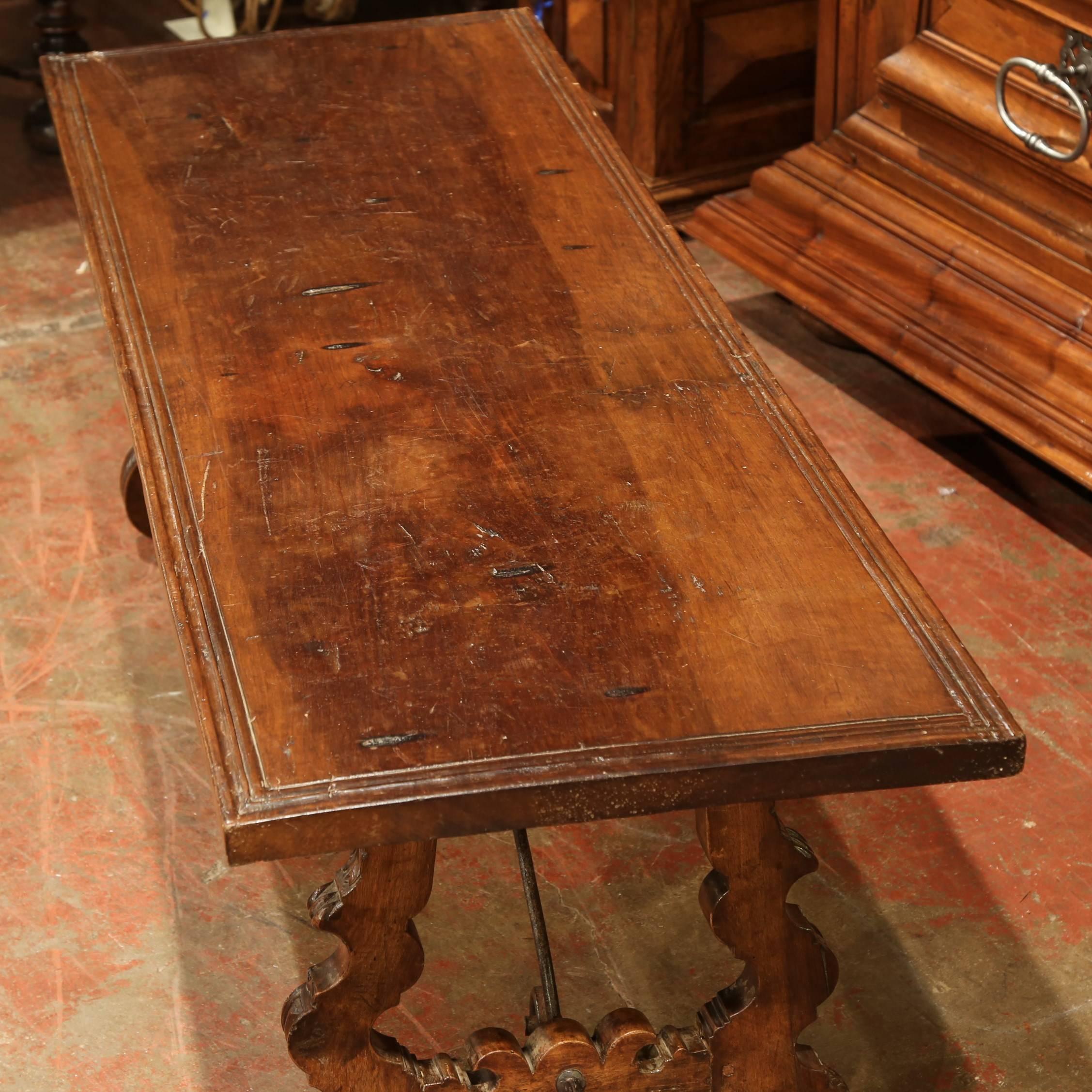 Complete your living room with this Classic, antique fruitwood coffee table from Spain, circa 1820. The table is supported by two carved legs, which are joined together with wrought iron stretchers. The tabletop is one piece of wood that has aged