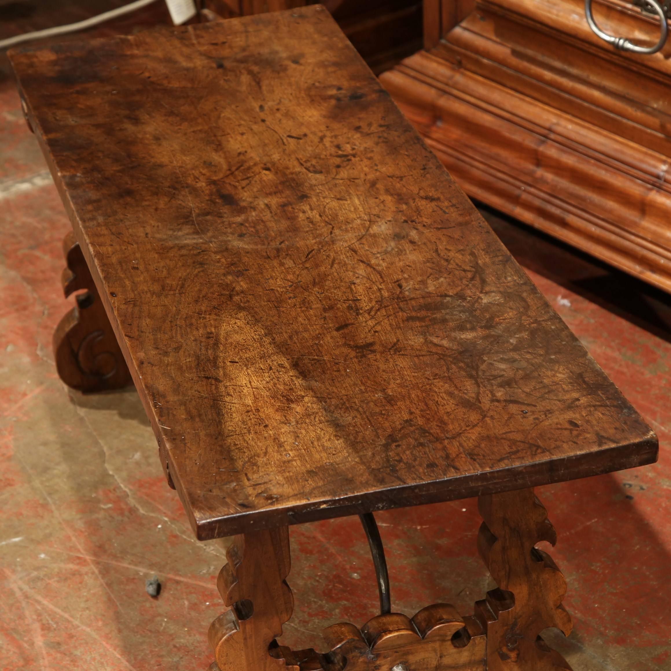Add extra surfaces to your family room with this beautiful, small coffee table from Spain. Carved, circa 1840, the fruit wood table features two carved legs with black forged iron stretchers. The top is made one single wooden plank. The table is in