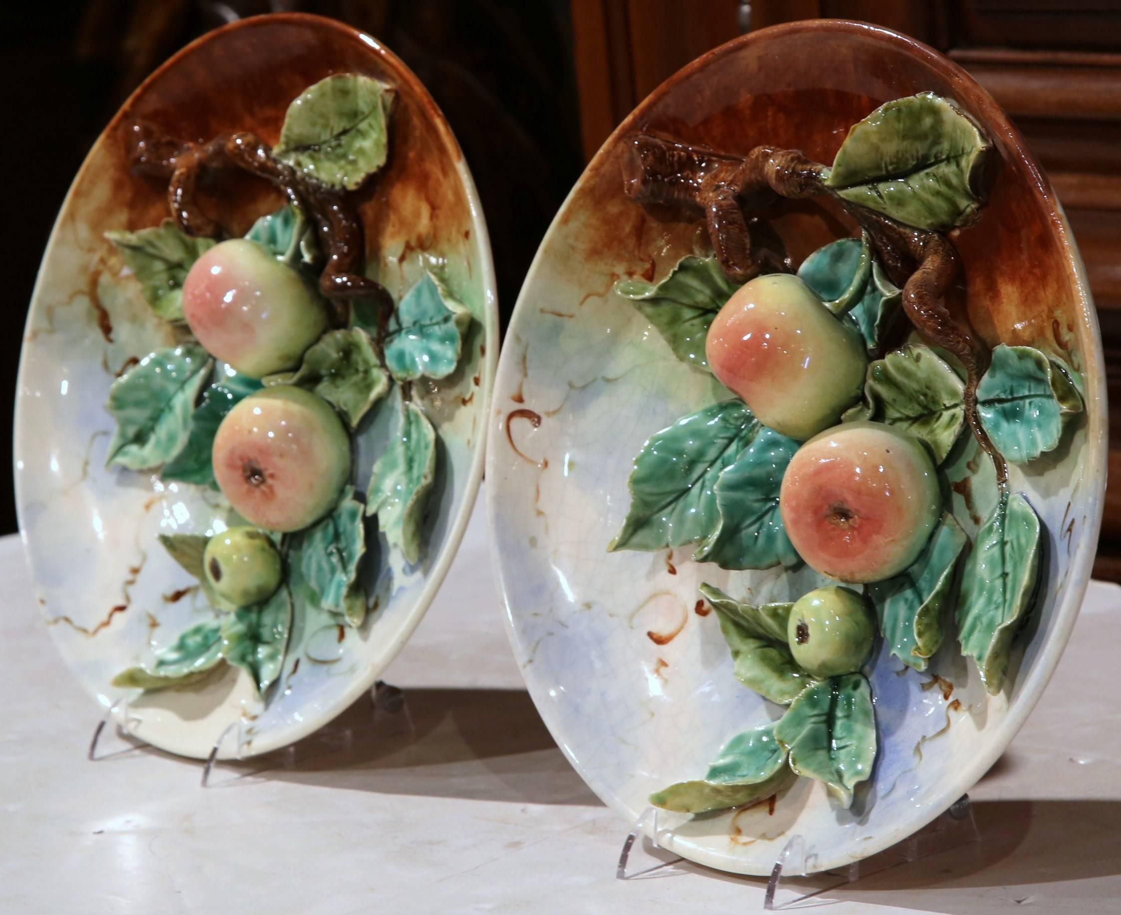 Perfect for a kitchen or dining room, this colorful pair of antique Majolica platters shows beautiful sculpted technique. The platters were crafted in France, circa 1880 and feature fruit branches with apples and leaf decor in high relief. The