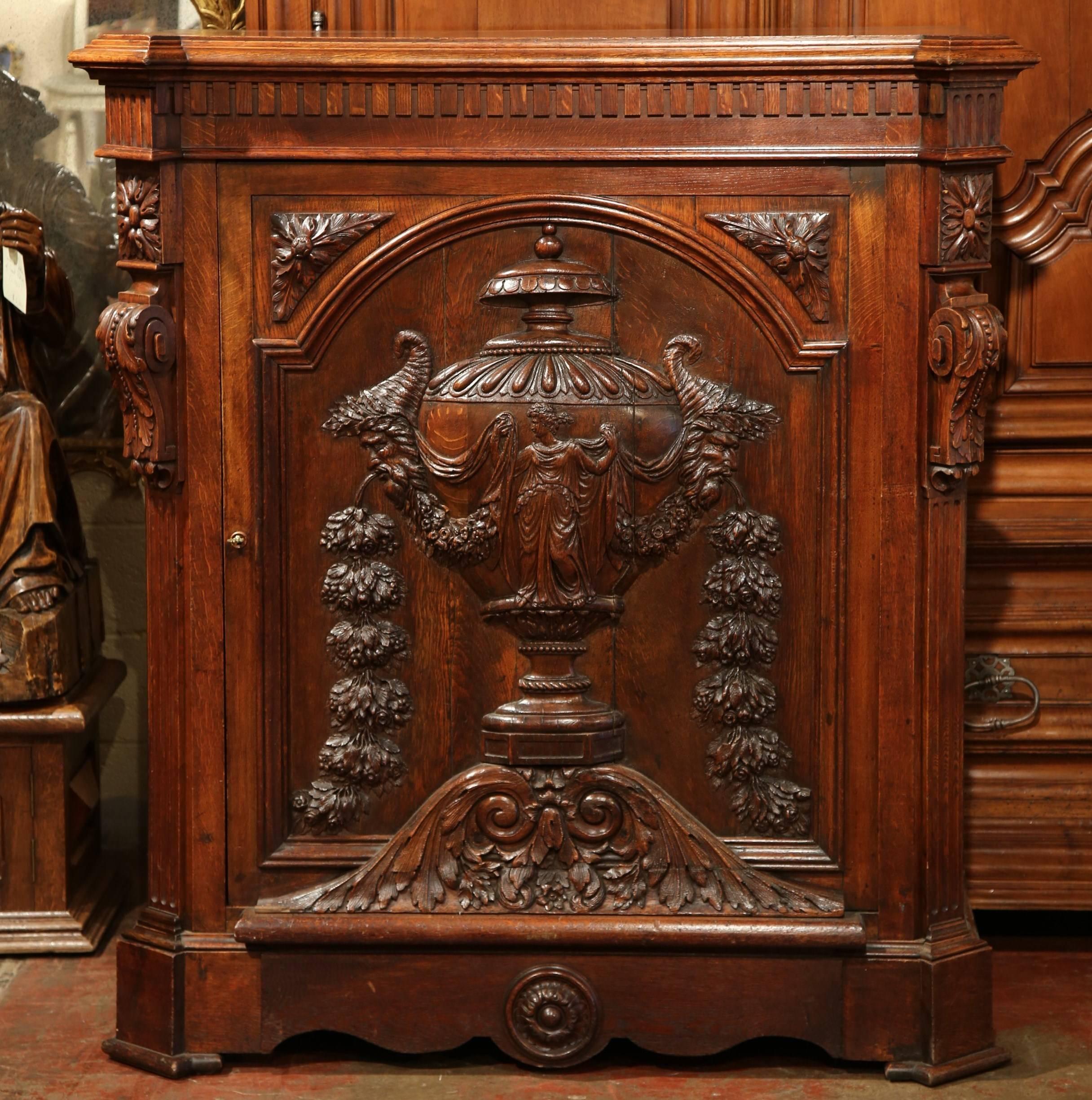 Keep your home organized with this 19th century carved cabinet. Crafted in France, circa 1870, this single door confiturier, or jelly cabinet, features a beautifully carved vase with floral swags on the central door, smaller carved details