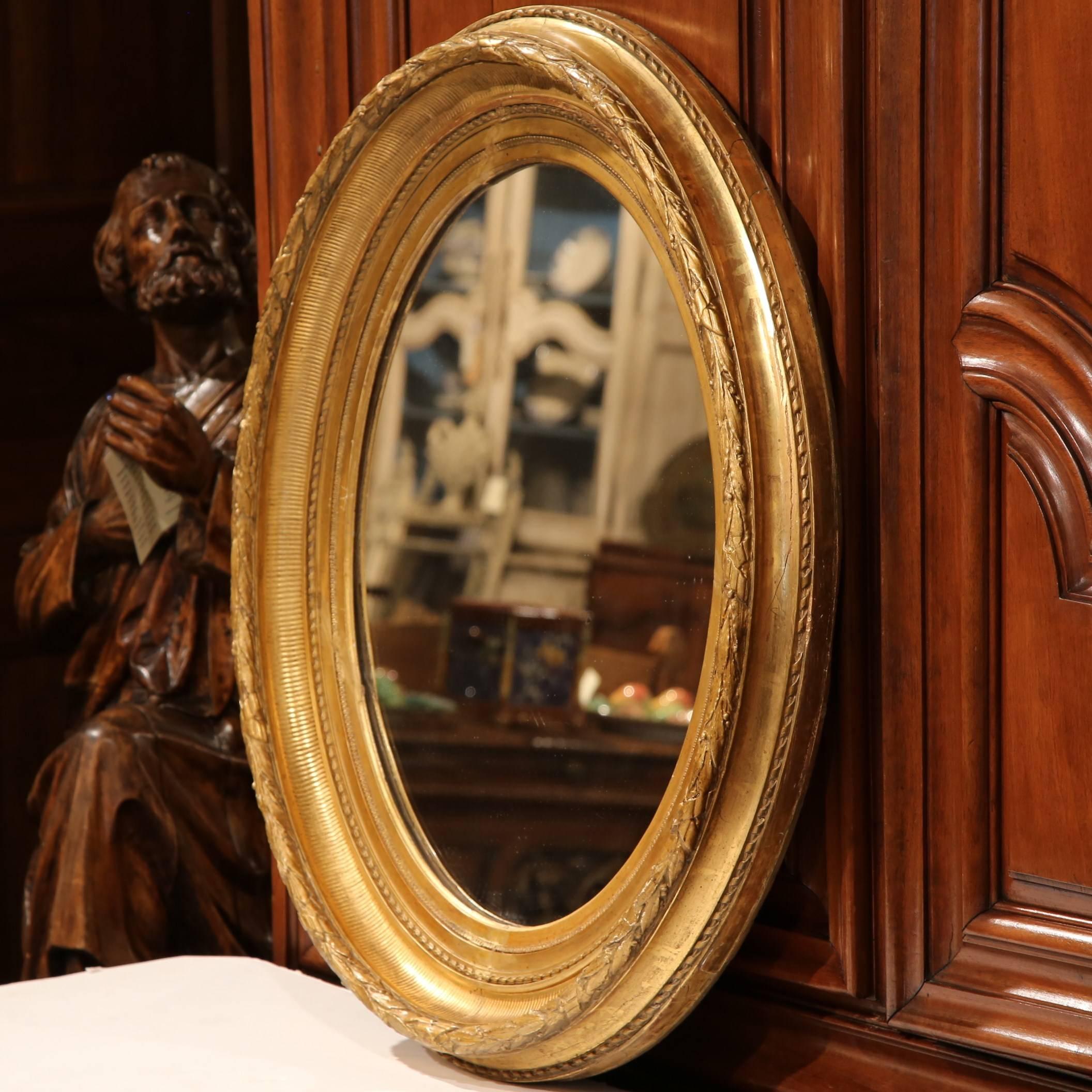 This elegant, antique carved mirror is a must-have for a home of any style from traditional to contemporary. Founded in Versailles, France, circa 1870, this oval mirror features intricate carvings around the frame with Classic motifs and is