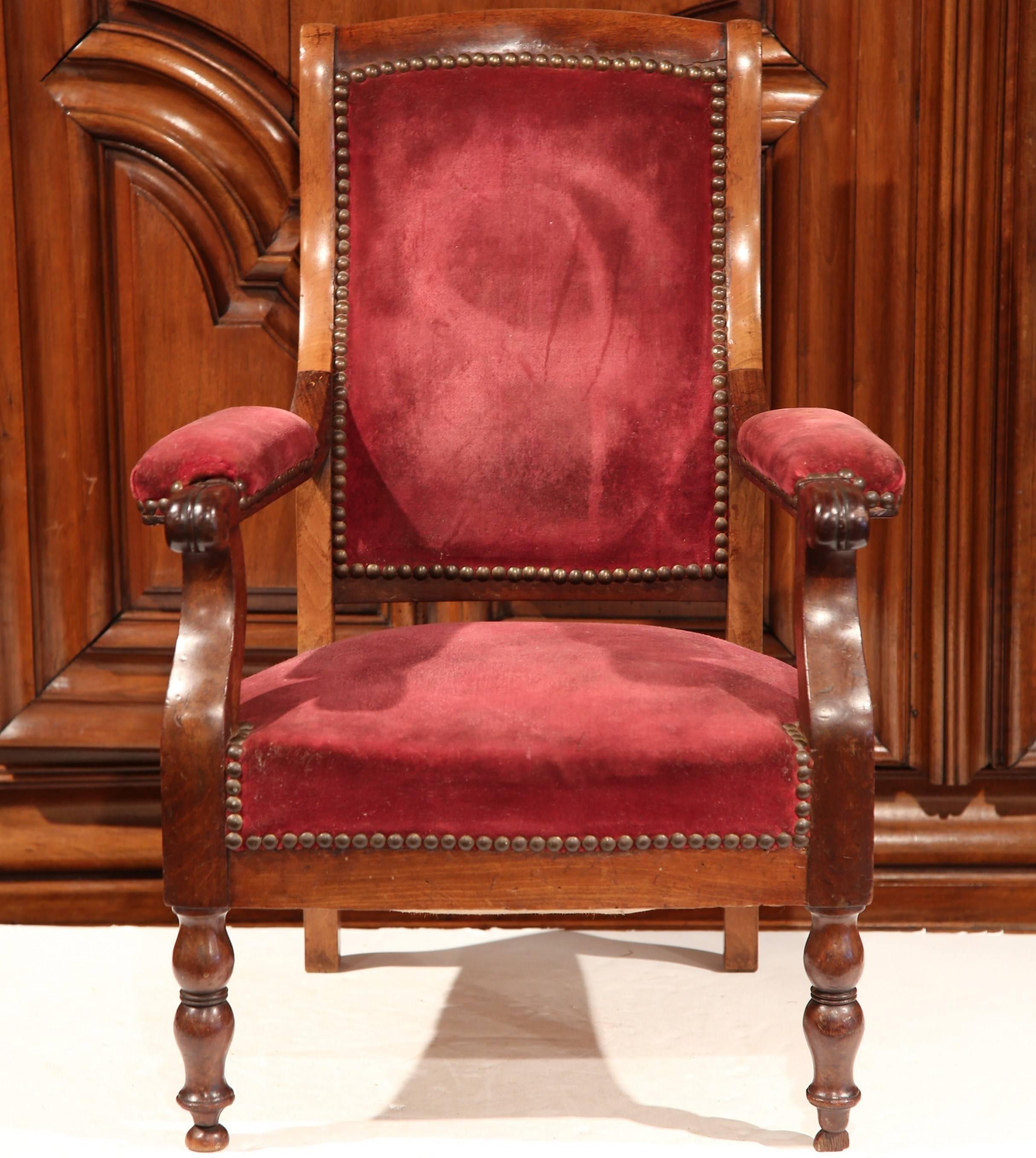 Add charm to a family friendly living room with this elegant, fruitwood youngster armchair. Carved in France, circa 1850, the antique chair has a high back, armrests and front turned legs, and is upholstered with a red velvet fabric, and embellished