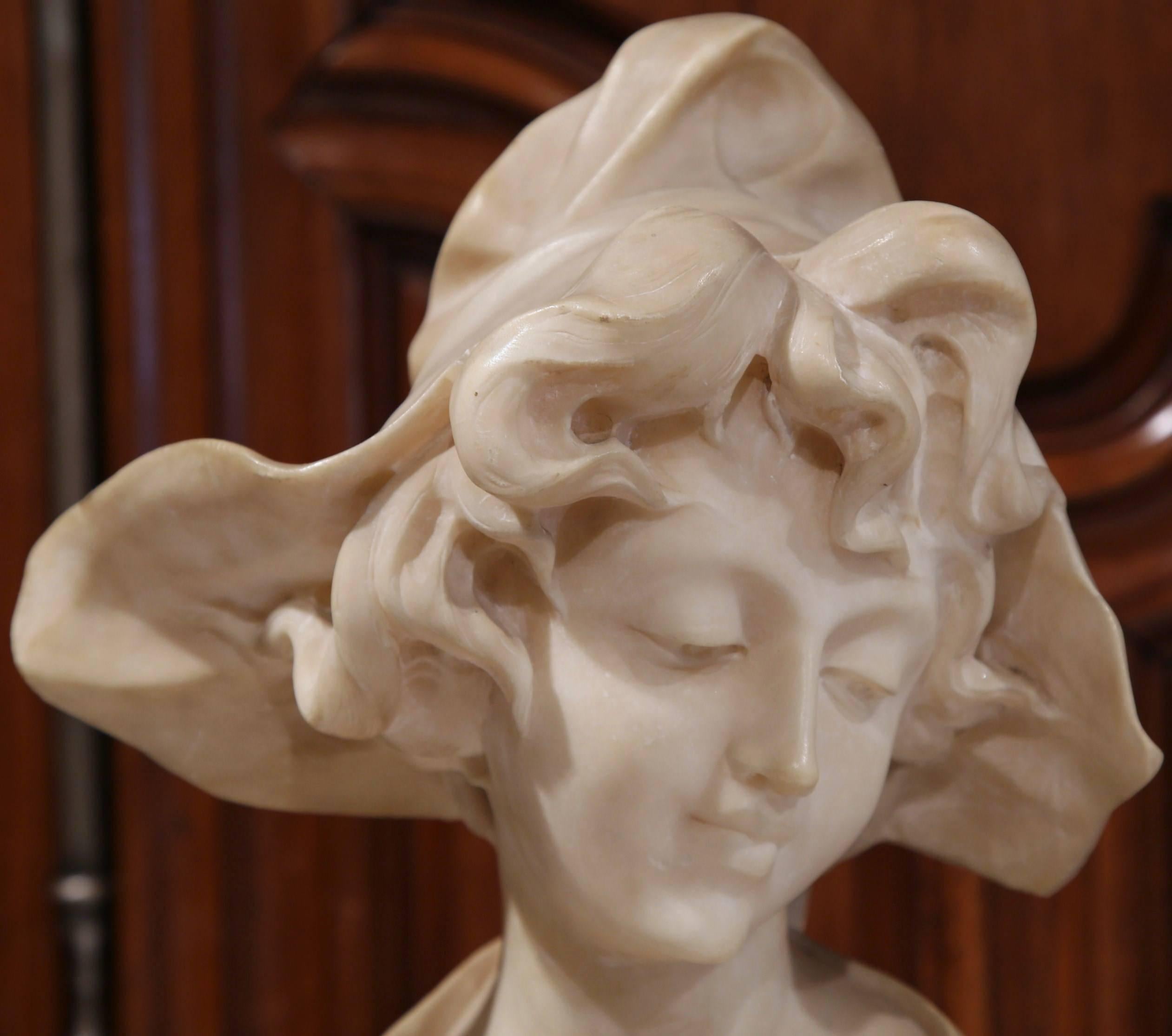 This antique bust is a classically French sculpture for a home of any style. The bust, sculpted circa 1860, features the serene face of a young woman wearing a bonnet and dressed in traditional clothing. The piece is white marble, has a beautiful