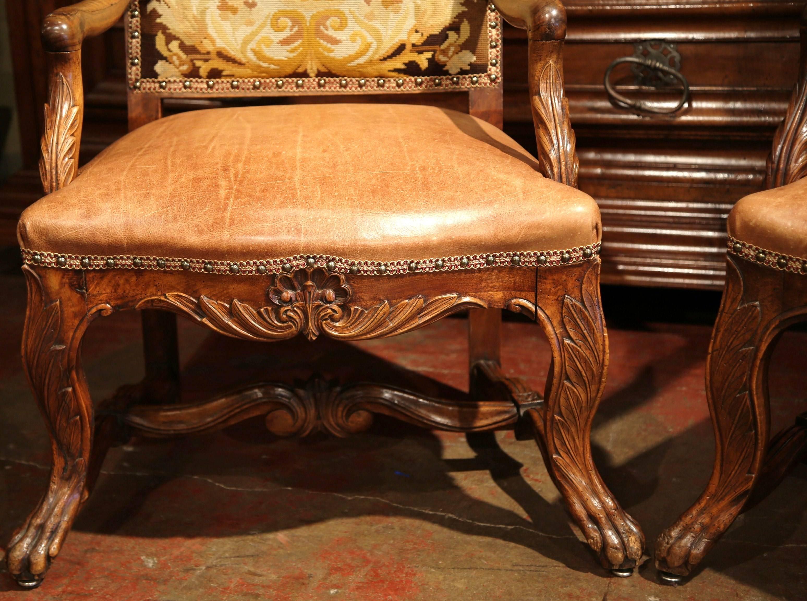These antique fruitwood armchairs were crafted in France, circa 1760, and would make an elegant addition to a living room, study or library. The chairs stands on cabriole legs ending with paw feet over a scalloped apron decorated with floral and