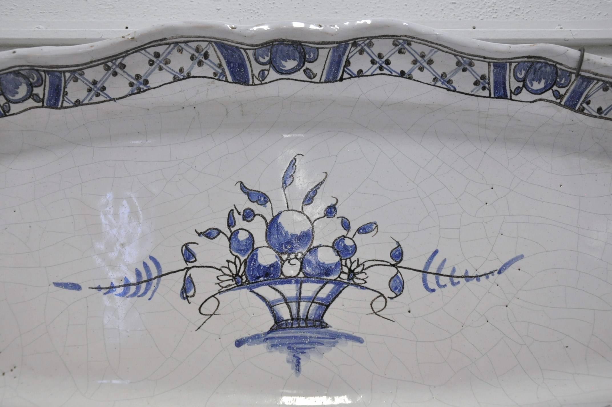 This large, antique, hand-painted platter was sculpted in Normandy, circa 1880. The oblong platter has a beautiful, Classic palette of blue and white, and has its original wall hanging hardware. At the center of the platter is a basket motif filled