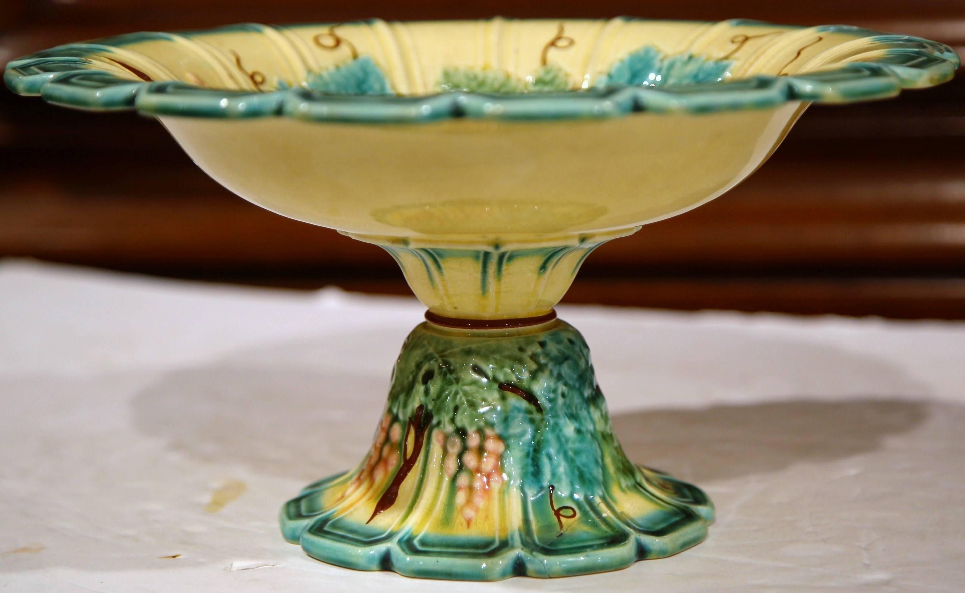 This beautiful, antique hand painted majolica centerpiece was sculpted in France, circa 1880. The blue, green and yellow dish features a wide cup with scalloped edges, resting on a tall carved round base. Both top and bottom are embellished with