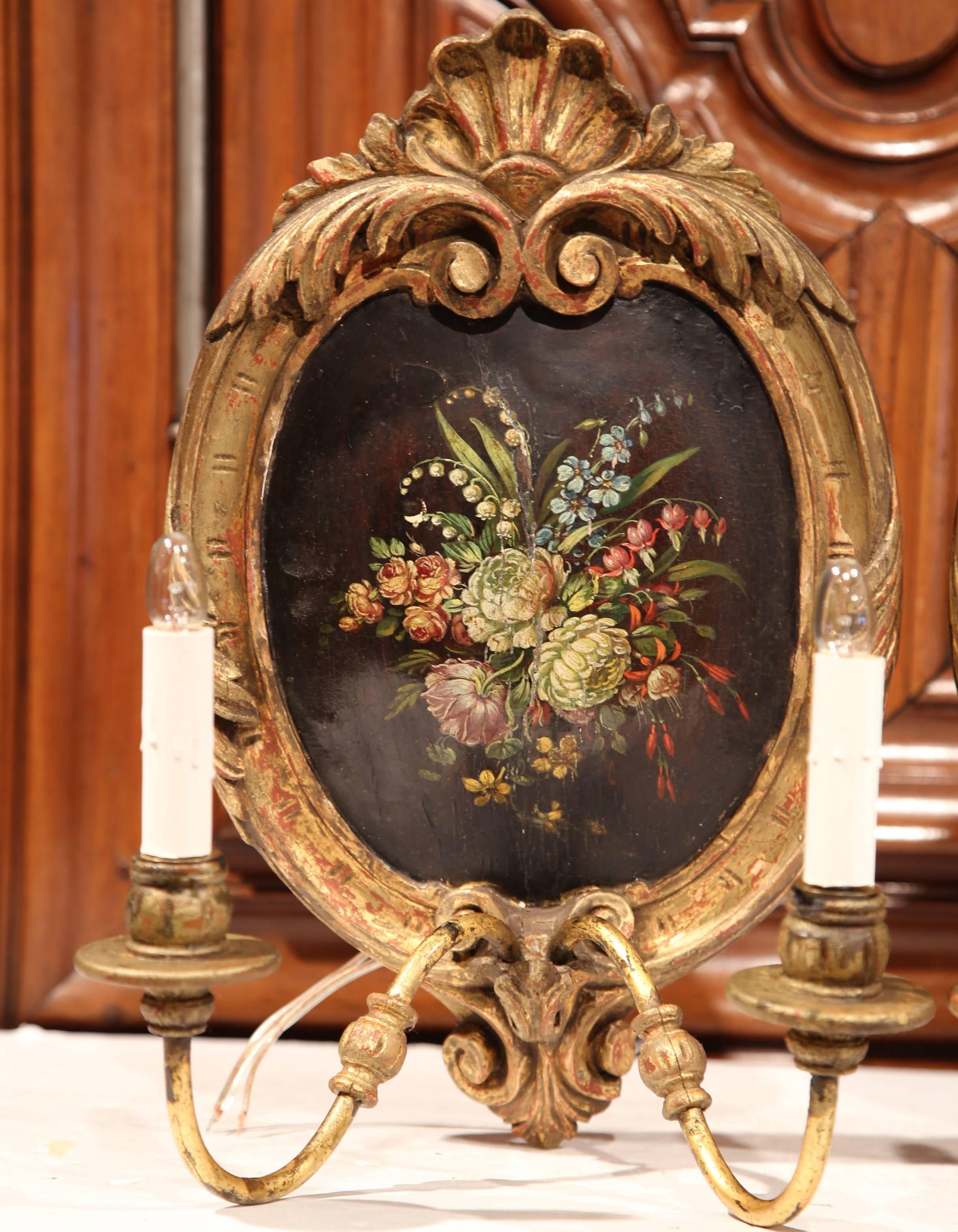 These elegant and colorful wood and metal antique sconces were created in Paris, France, circa 1880. The two-light fixtures are set apart by their hand painted center oval medallions, which feature a colorful bouquet of flowers and leaves on a black