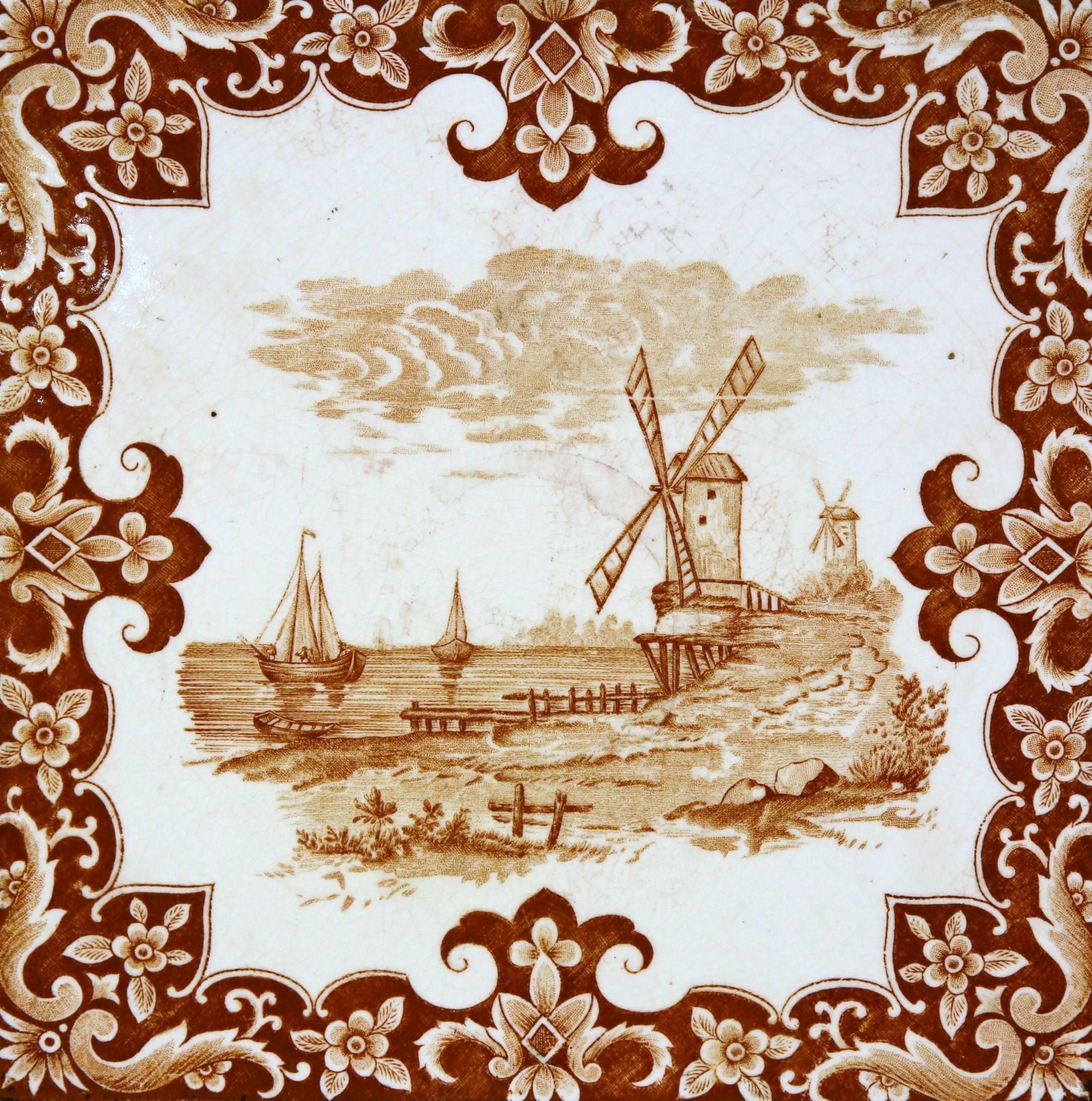 This interesting, antique hot dish tray was crafted in France, circa 1870. The piece features a hand painted centre tile with a windmill and sailboats in a brown and white palette. The ceramic tile is set inside a carved wood frame. The tray