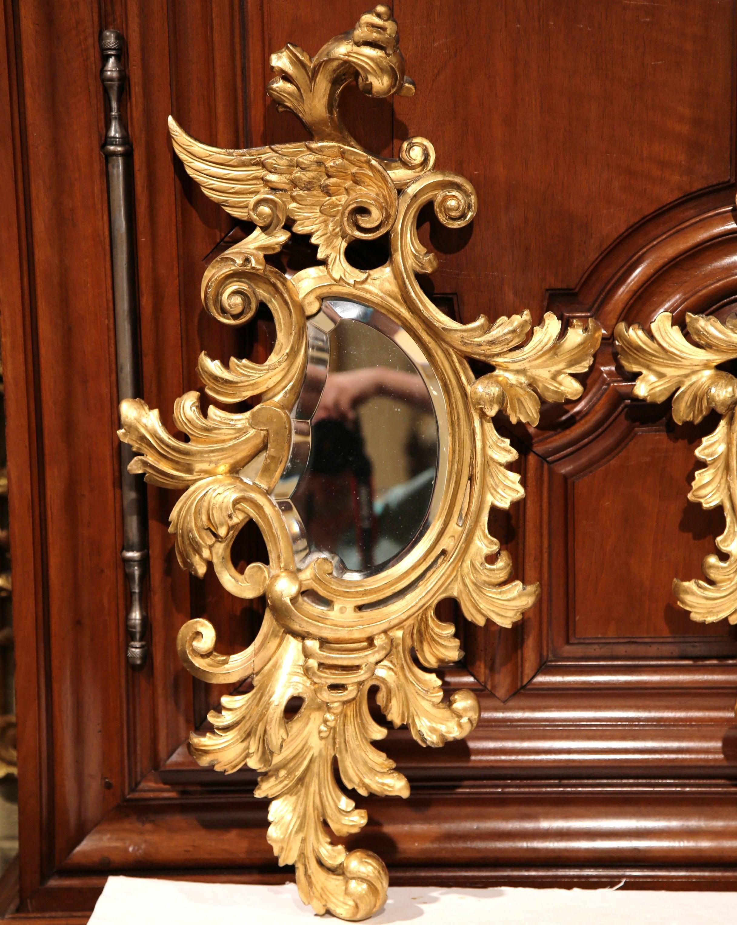 This beautiful pair of tall antique wall hanging mirrors was created in France, circa 1860. Both mirrors are set inside a cartouche shaped frame that feature hand-carved leaves and wings with their original gold leaf finish. The beveled glass is in
