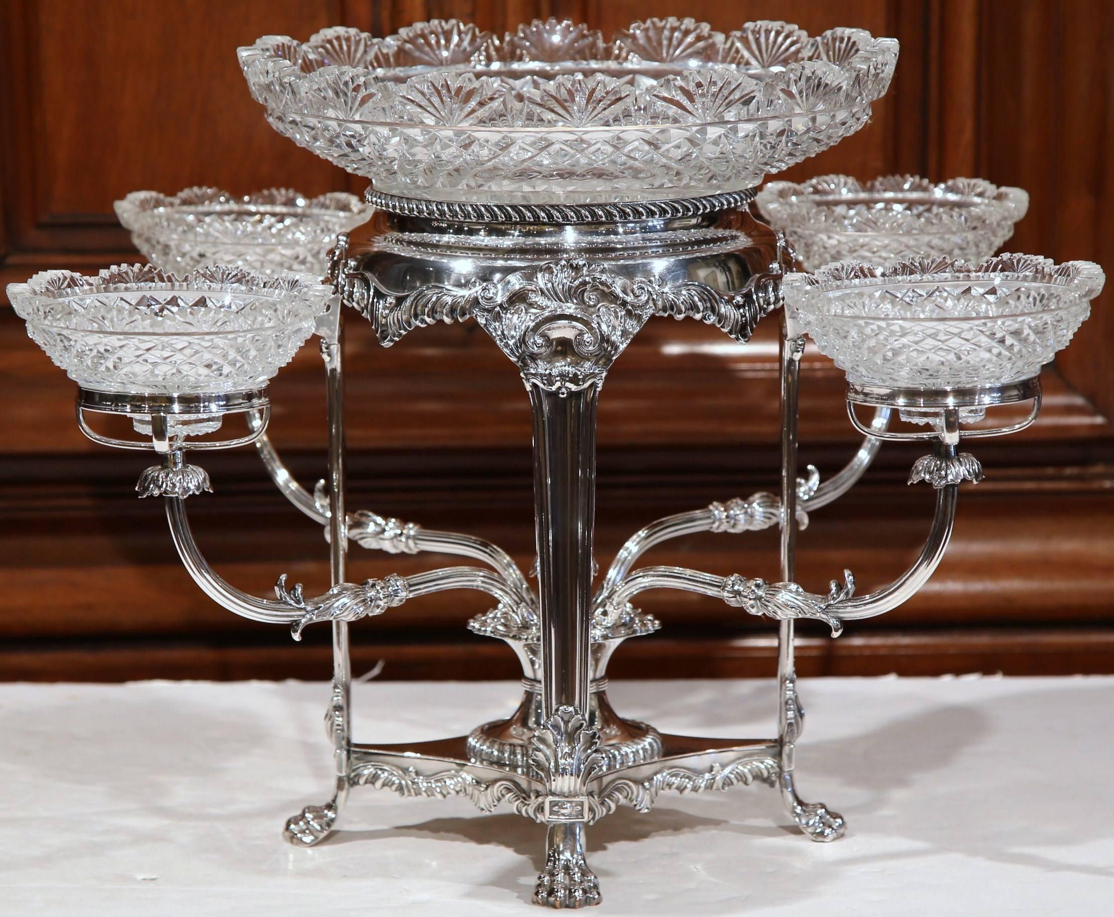 This elegant silver-plated epergne was created in England, circa 1870. The ornamental centerpiece features a large cut-glass bowl in the center with four smaller cut-glass coupes around. There are no apparent markings, and the piece is in excellent