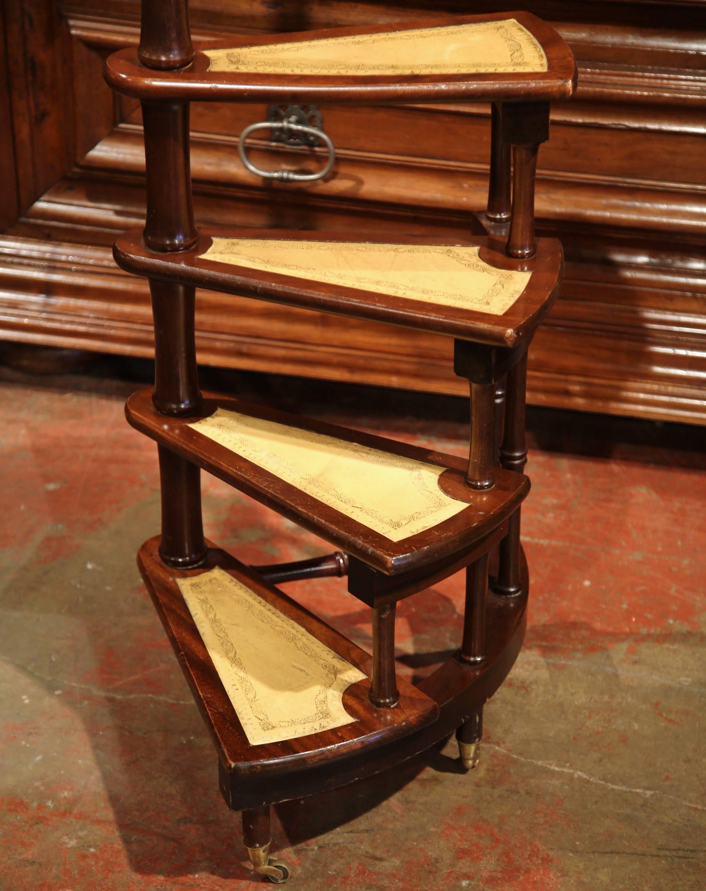 This set of vintage mahogany library stairs were created in England, circa 1950. The thin steps come from a central, circular steps and spiral out for extra height with a slim profile. The steps are covered with leather and tooling, and has a brass