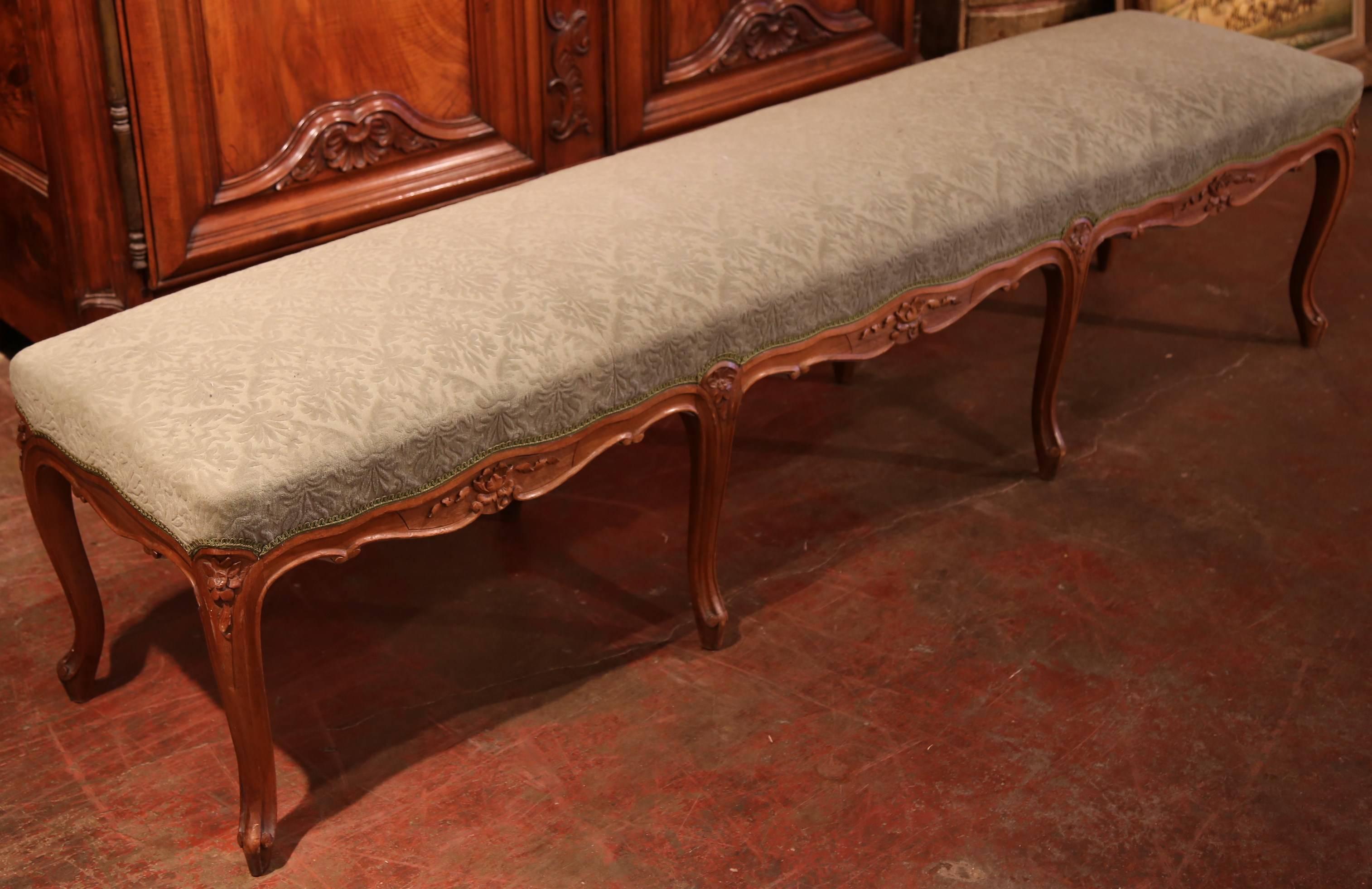 Incorporate elegant seating into your entryway or bedroom with this antique fruitwood bench. This bench without back were created in Paris, France, circa 1880 and feature eight cabriole legs and a carved apron on both sides. The bench is upholstered