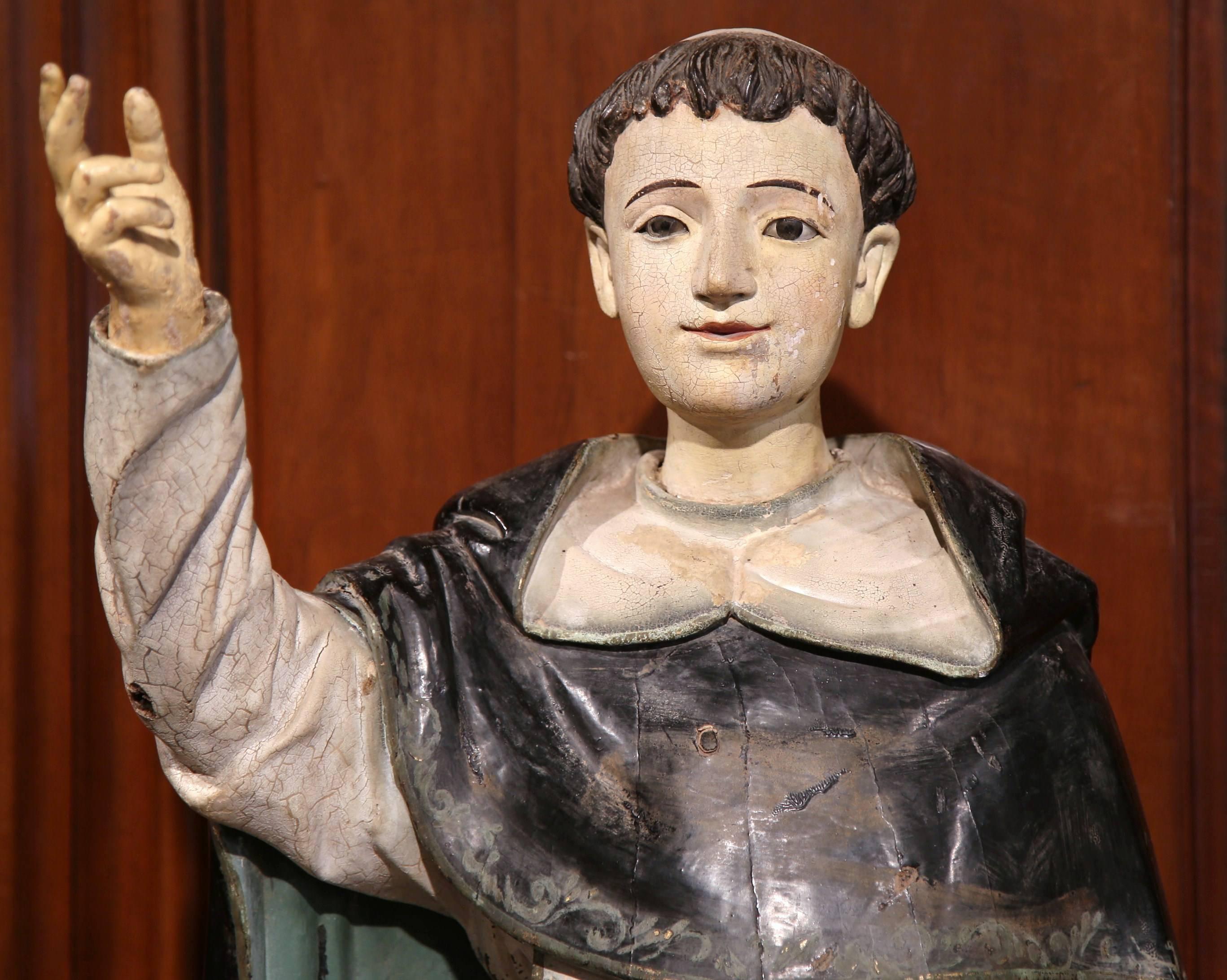 This beautiful statue of Saint Thomas of Aquin (or Aquinas) was sculpted in Italy, circa 1720. The tall religious figure stands on a wooden base, holding a theology book in one hand and raising the other like he is teaching a class. The colorful