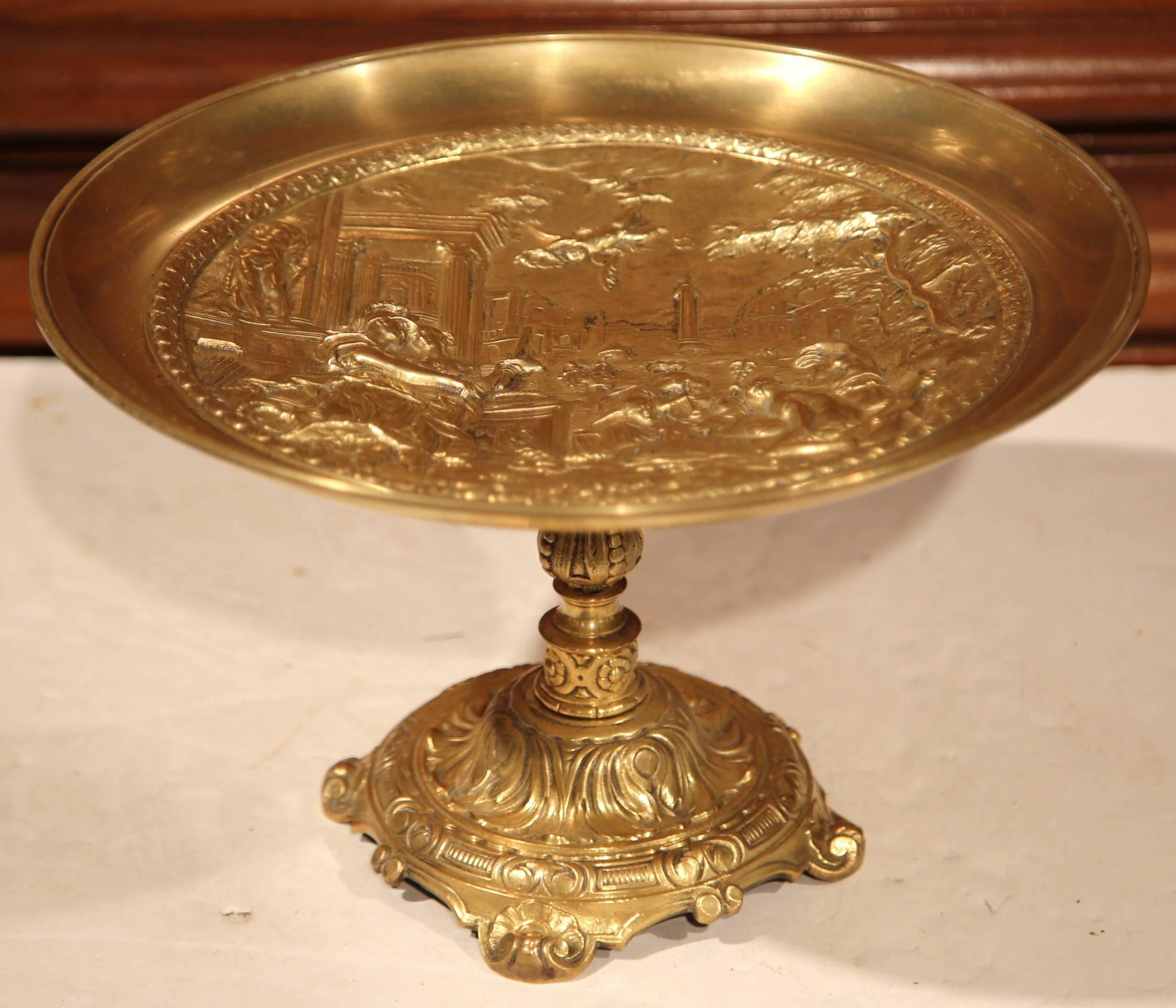 This elegant, antique bronze centrepiece was crafted in France, circa 1920. The shallow dish sits on an intricate base with scroll feet, and the inside of the bowl is decorated with a traditional Roman scene with muses talking, reading and dancing.