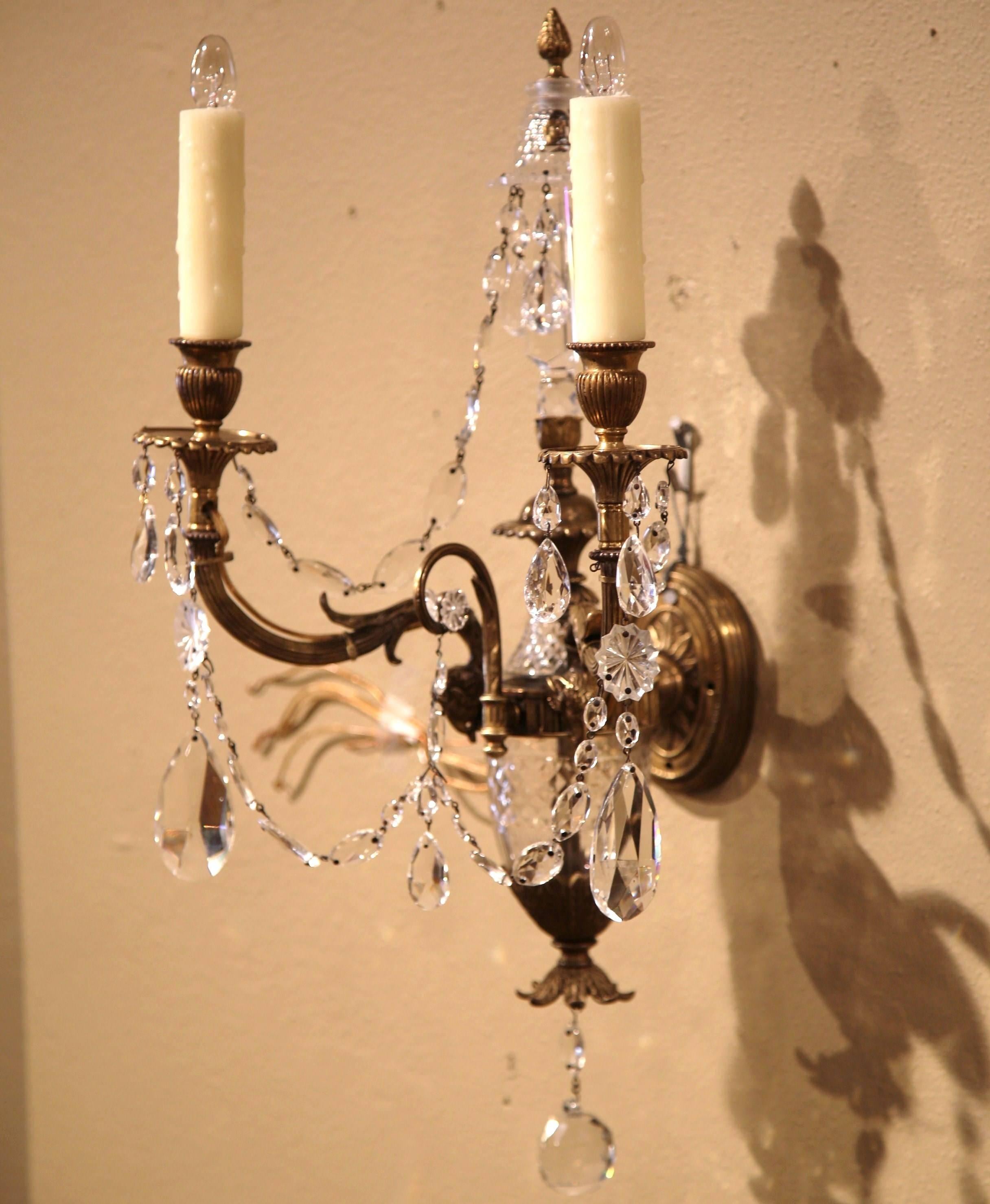 Light up your home with this elegant pair of antique wall lights from France, circa 1880. The sconces each feature two intricate bronze arms with ram heads, cut-glass swags and other beautiful glass decorations. Both fixtures have new wiring