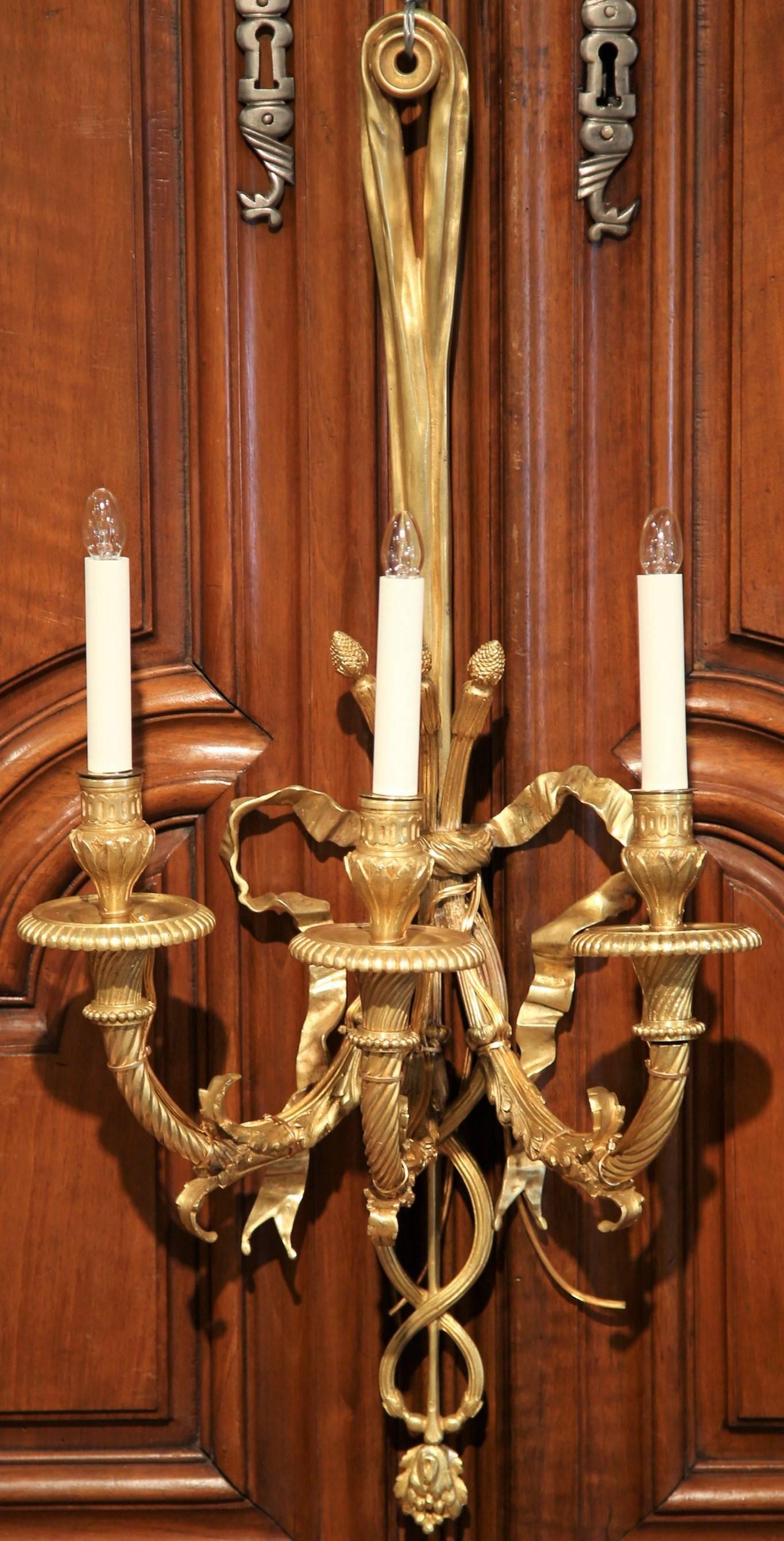 This pair of elegant bronze sconces was created in France, circa 1870. The large wall lights have three twisted arms newly wired and feature the traditional Louis XVI ribbon bow embellished with intricate scroll work on the bottom. The fixtures are