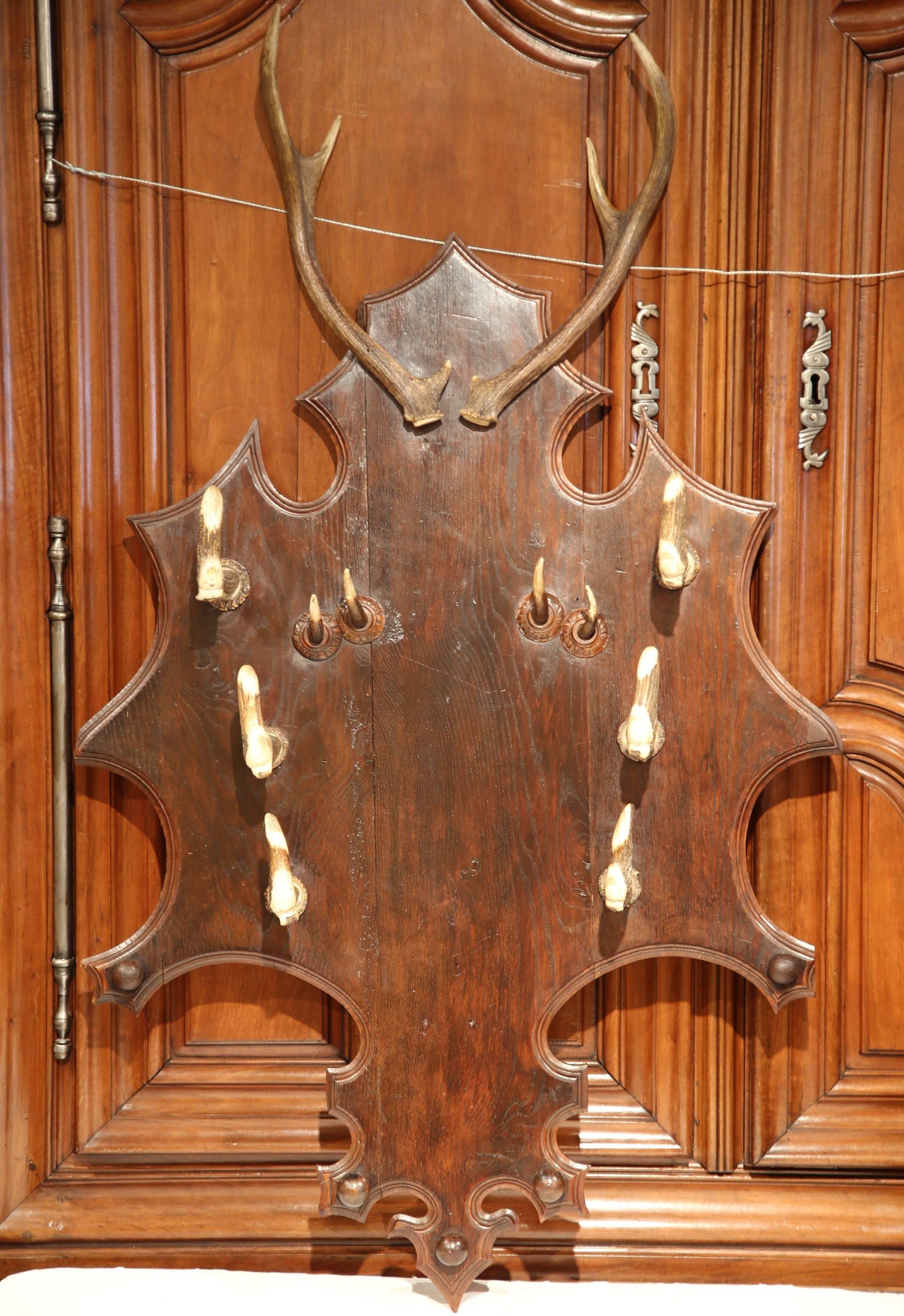 This antique, wood hanging rack was carved in the Pyrenees of France, circa 1880. The unique piece has a pair of antlers at the pediment, and different species of horns below on the plaque. The wooden wall rack could be used to hold three guns