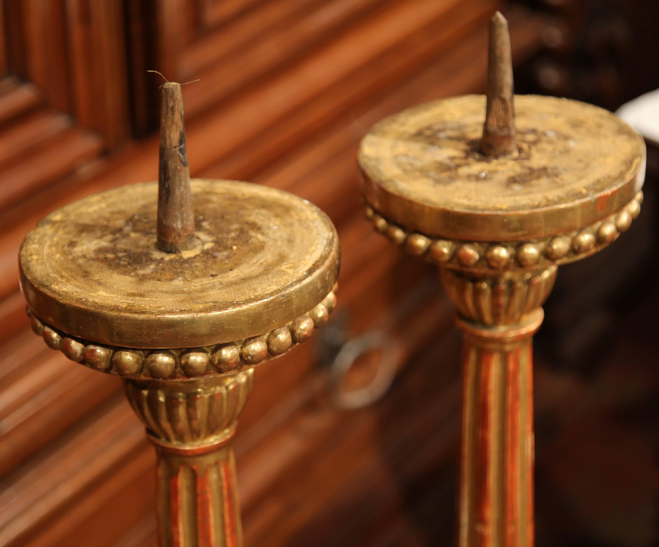 Add elegance to your home with this important pair of antique gilt candlesticks. Carved in Italy, circa 1850, each tall candleholder stands on small feet over a sturdy triangle base with carved medallion on all sides; the long, decorative stem is