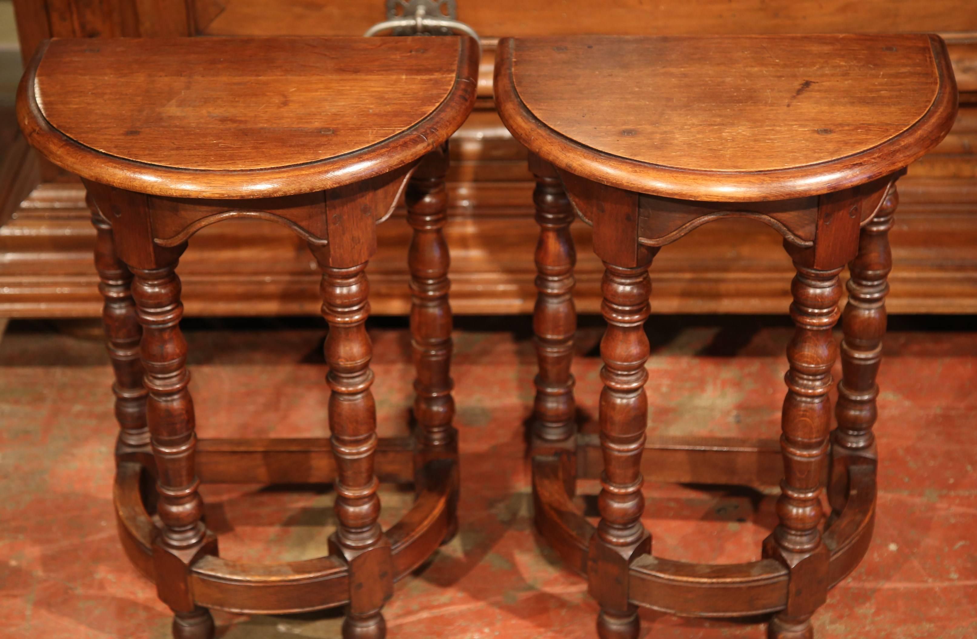 This fine pair of fruitwood side tables was carved in France, circa 1930. Each table is shaped as a semicircle with four turned legs and a half circle stretcher. The Classic, wood occasional tables are in excellent condition with a rich walnut