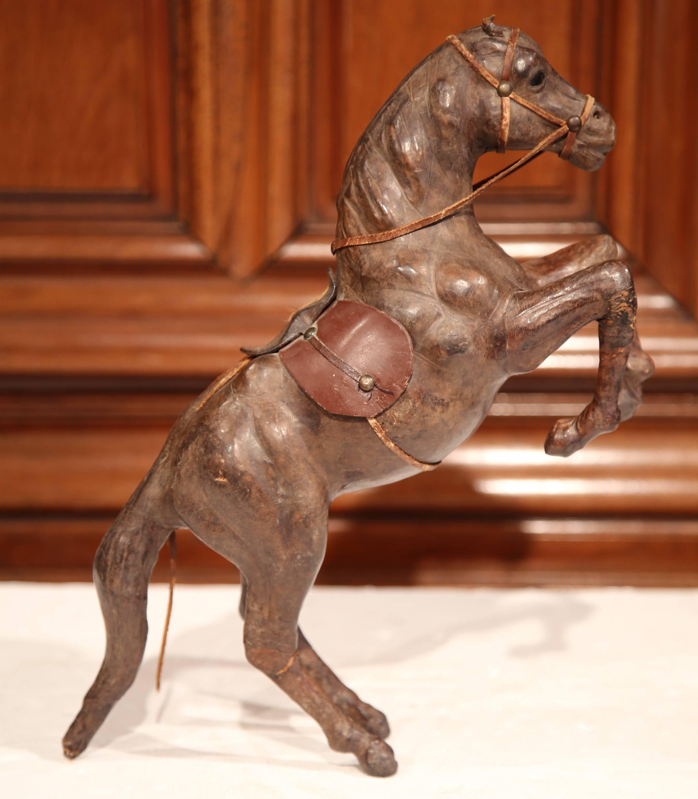 This beautiful, antique horse sculpture was crafted in France, circa 1880. The rearing horse figure stands on his back legs and is dressed in traditional equestrian dressage accessories including a halter, bridle and saddle. The detailed leather