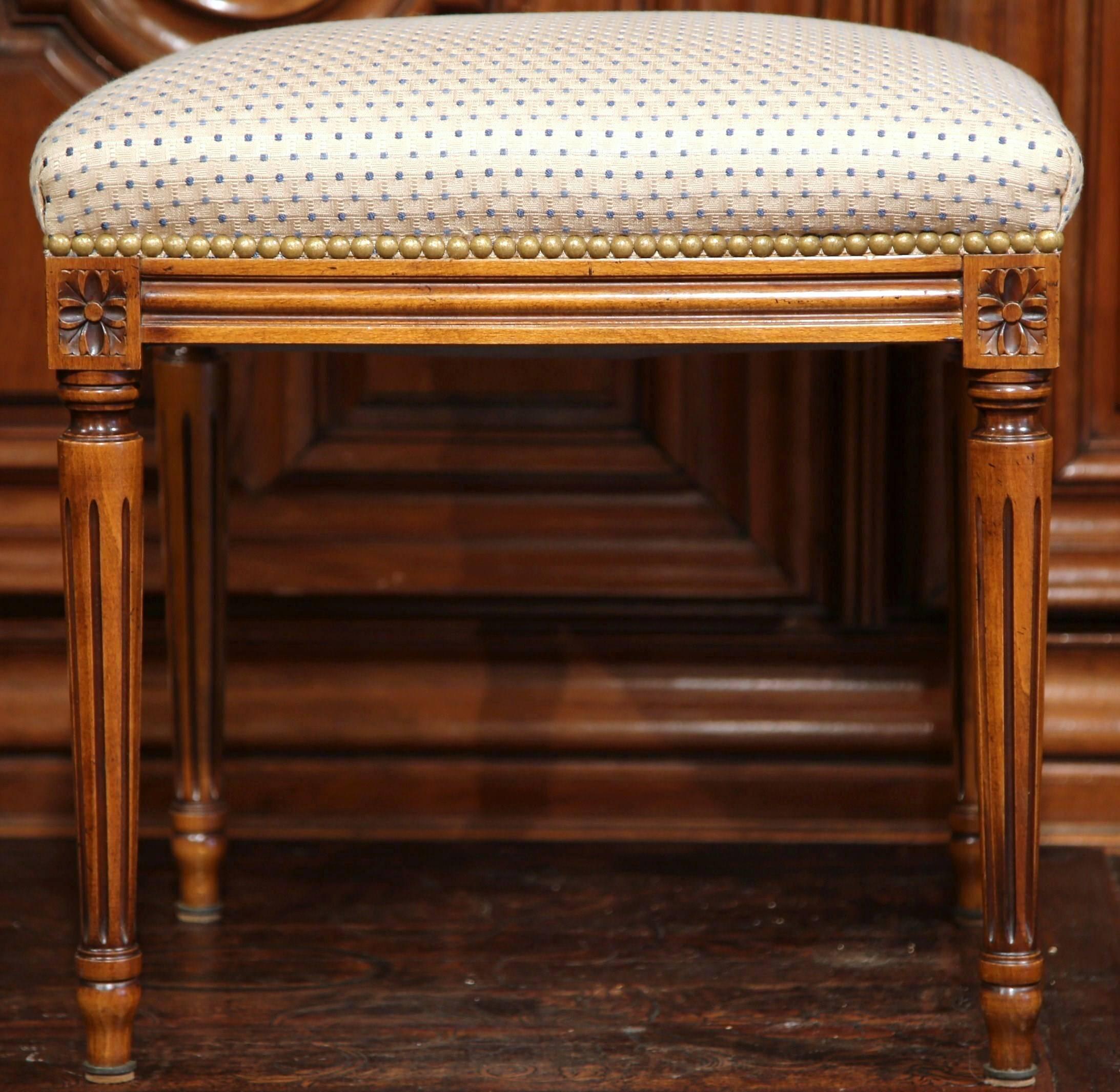 This elegant fruitwood stool was carved in France, circa 1920. The small seat has four tapered legs with delicate flower medallions in each corner. The seat has been reupholstered with an elegant white fabric with a subtle dot design. Incorporate