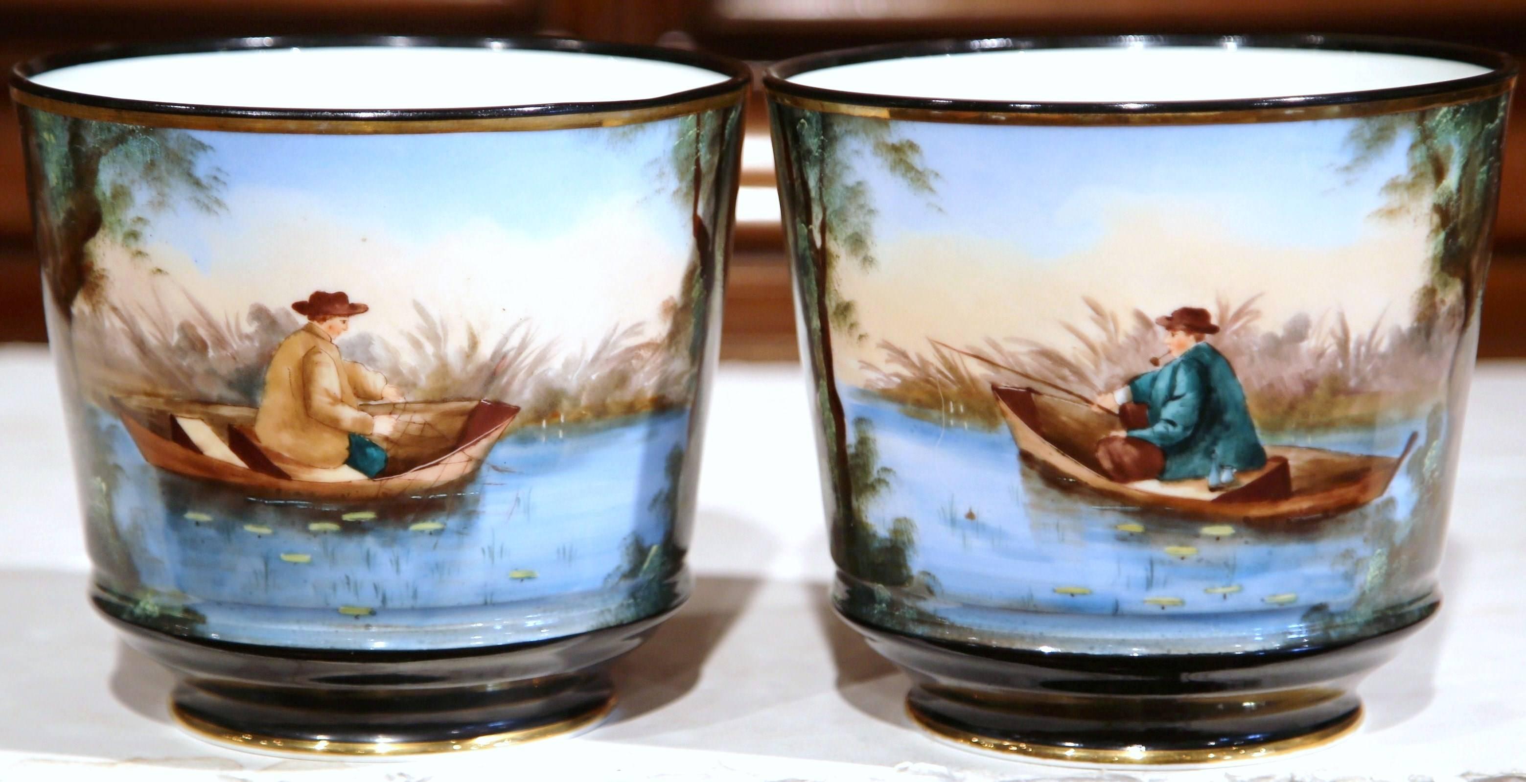 Bring a little color into your home with this pair of elegant, antique porcelain planters. Crafted in France circa 1870, the ceramic pots each show a handpainted fisherman in his boat. Each Limoges style porcelain cache pot has a gold rim on top and