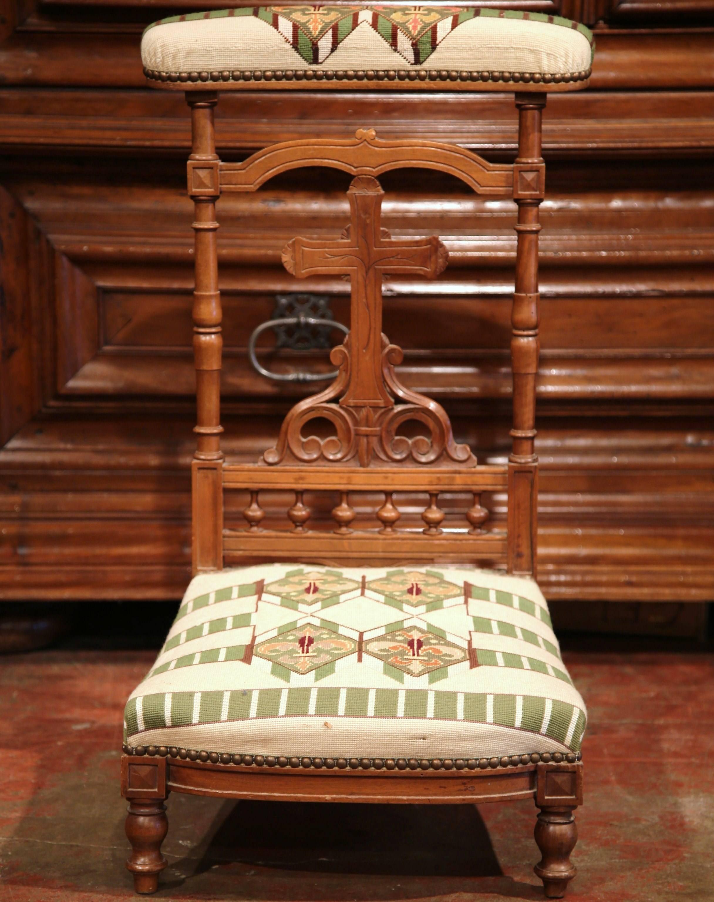 This elegant fruit wood prayer chair from a private chapel was crafted in France, circa 1880. The kneeler features a large hand carved cross supported with a row of spindles. It is upholstered with a hand-made needlepoint tapestry with fleur-de-Lys