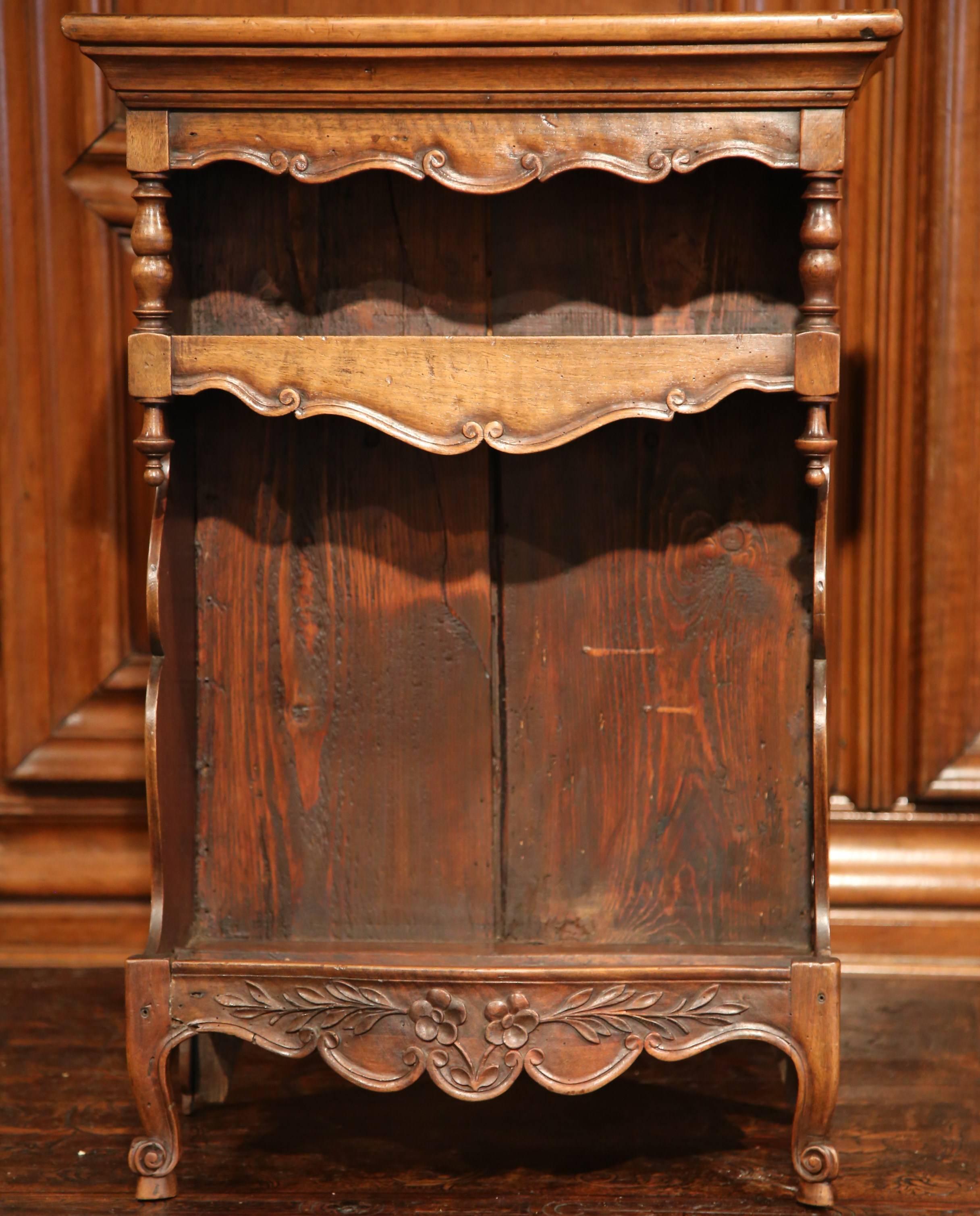 This elegant, small, fruitwood antique cabinet was crafted in Avignon, France, circa 1870. Made out of walnut, the open shelf sits on small front scroll legs with escargot feet, and features a scalloped apron embellished with floral and leaf motifs.