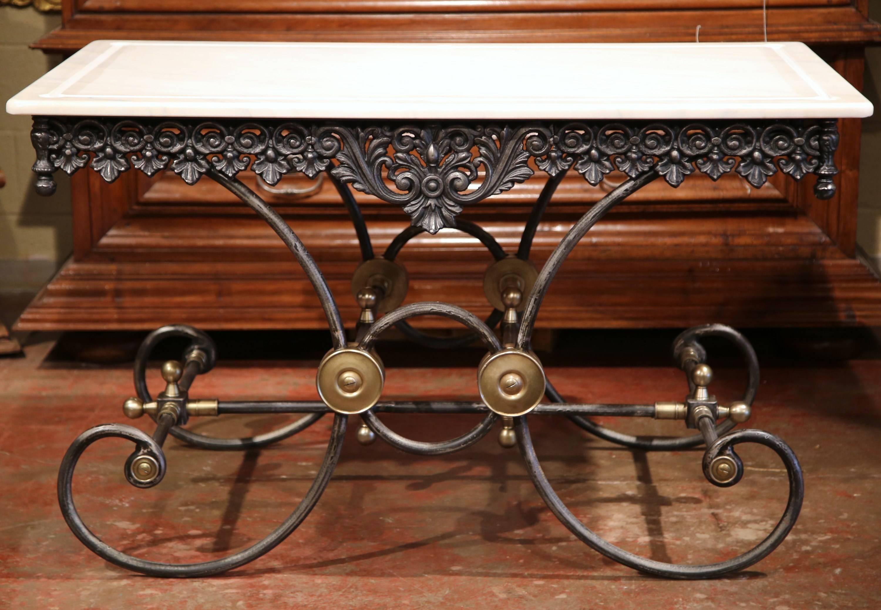 This large French butcher table (or pastry table) would add the ideal amount of surface space to any kitchen. This table has a polished iron finish and features a scalloped apron with intricate metal work, beautiful scrolled legs and brass mounts.