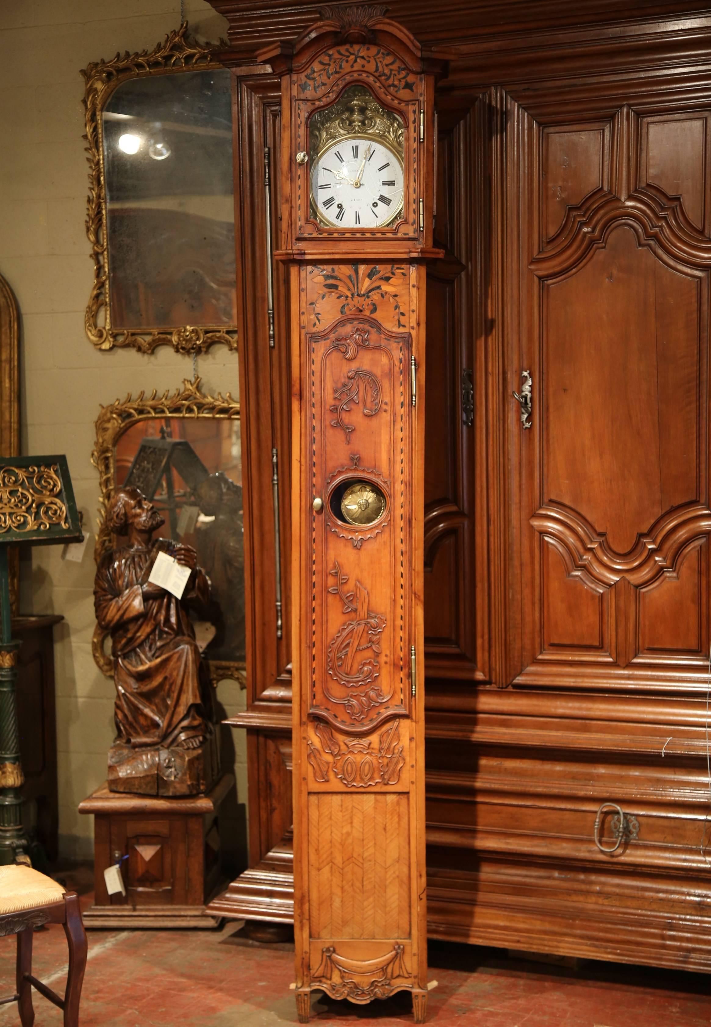 Make a grand statement in a living room or entryway with this elegant, antique morbier clock. Crafted in the Poitou region of France, circa 1780, the traditional tall grandfather clock has an arched top and beautifully carved motifs with inlay work
