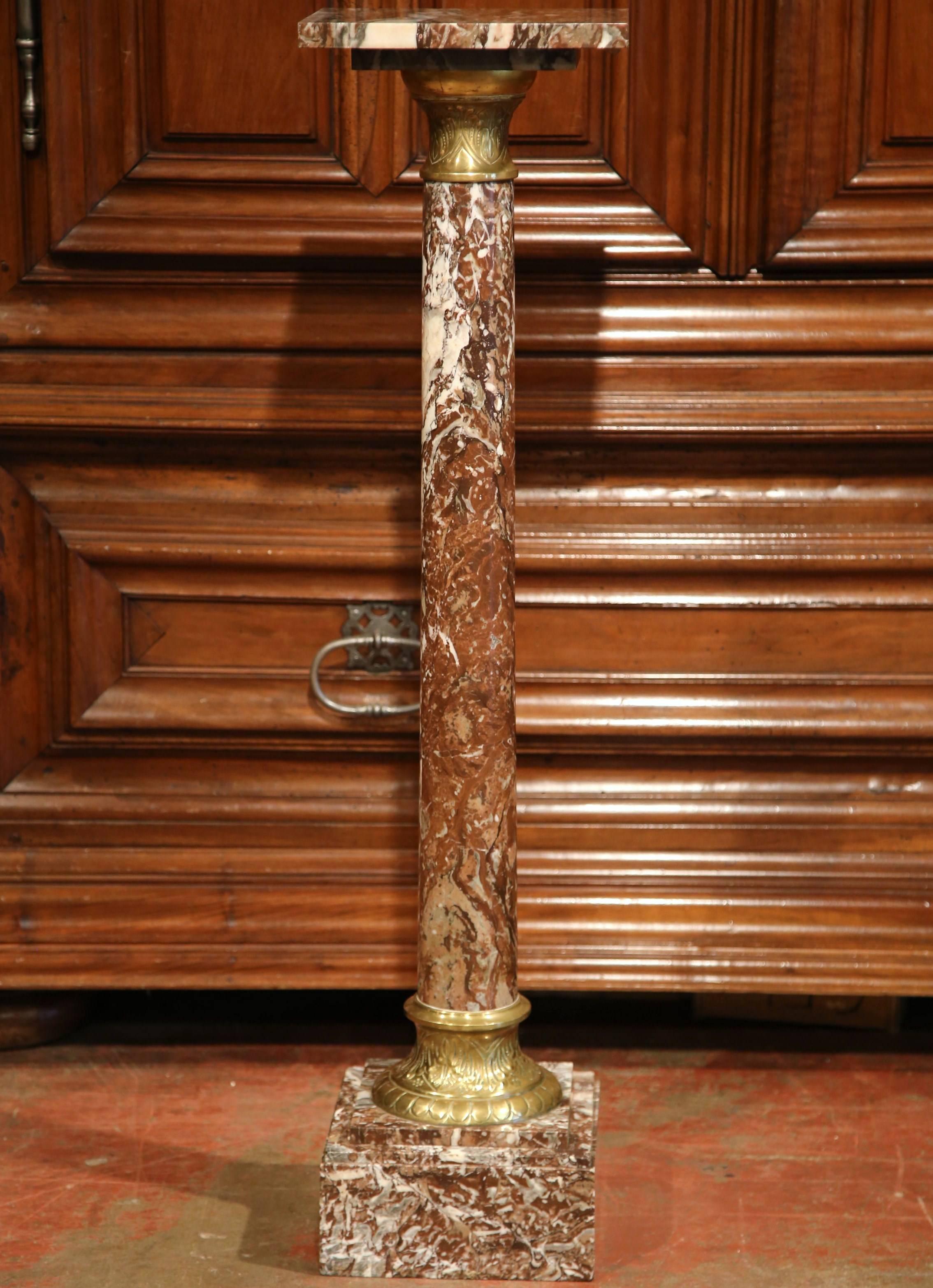 This elegant antique red marble pedestal was crafted in France, circa 1870. The pedestal sits on a sturdy square base with a repousse brass ring at the bottom, and features a tall round stem embellished by ornate brass mounts at the neck. It is