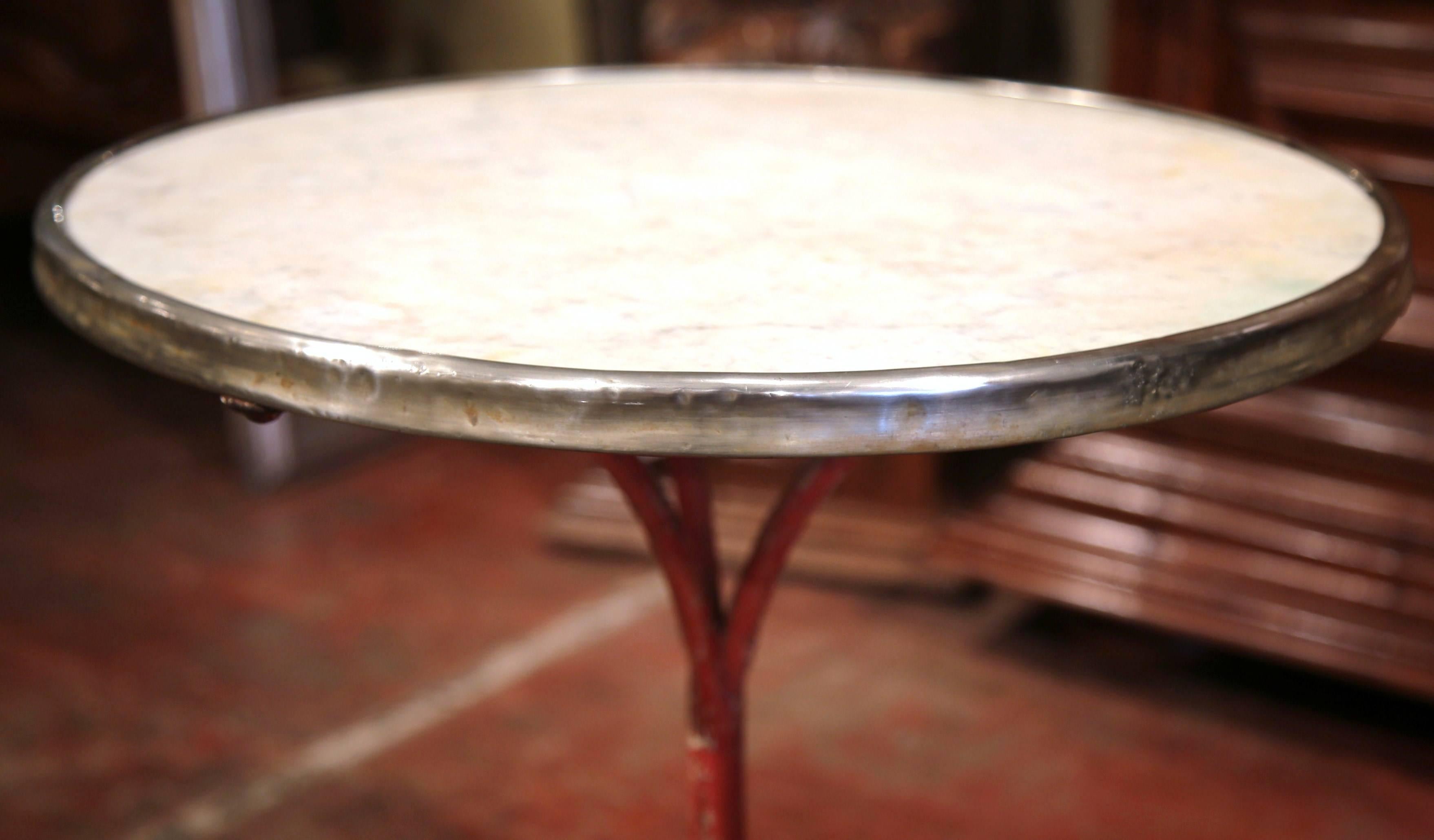 This exquisite, antique gueridon was crafted in Paris, France, circa 1870. The Classic bistrot table features its original, round white marble top embellished by a circular brass trim and has a long, thin iron base finished with three paw feet at