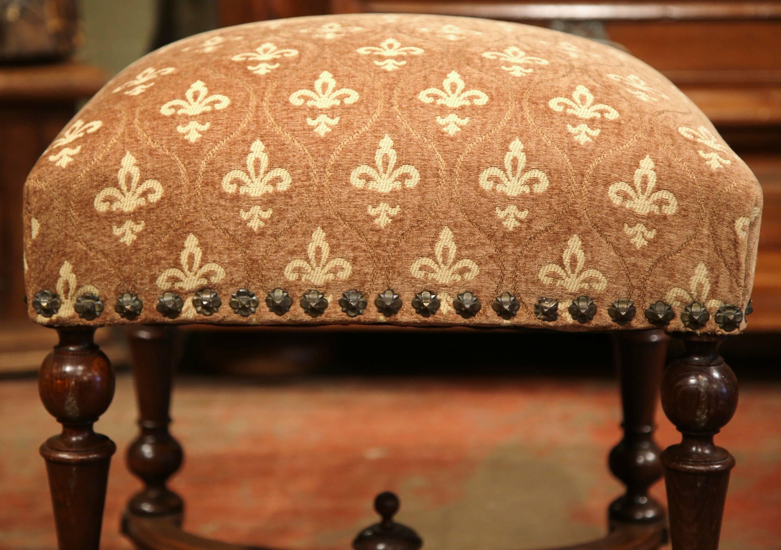 This elegant, antique fruitwood stool was crafted in Southern France, circa 1860. The comfortable, plush Louis XIII stool features four turned legs stabilized by a cross stretcher and embellished with a decorative center finial. The square, raised