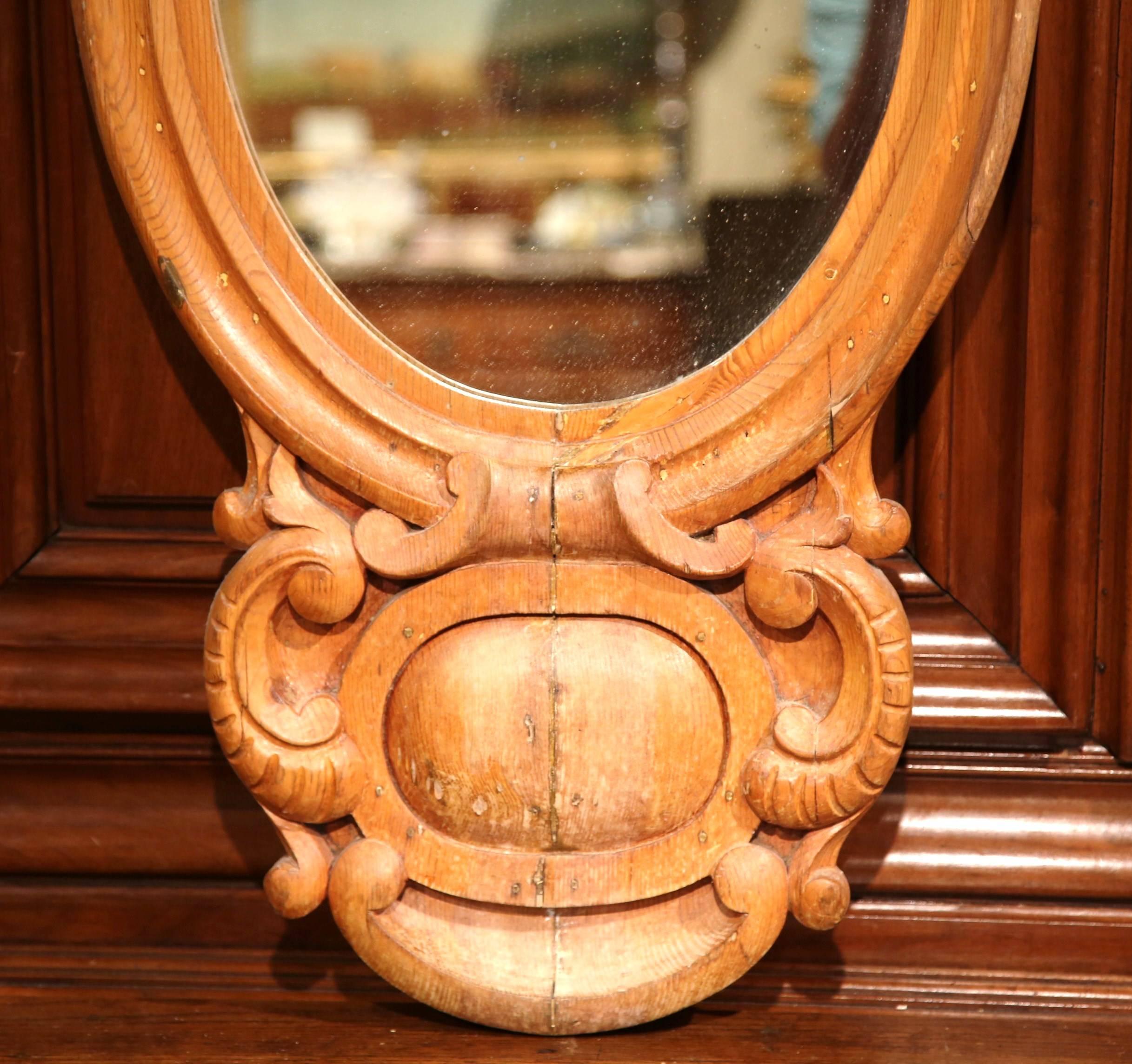Decorate your powder room or entryway with this elegant, antique wall mirror from England. Crafted, circa 1860 and made of pine, the mirror features a carved shell at the pediment, an oval mercury glass in the center and a carved medallion motif at
