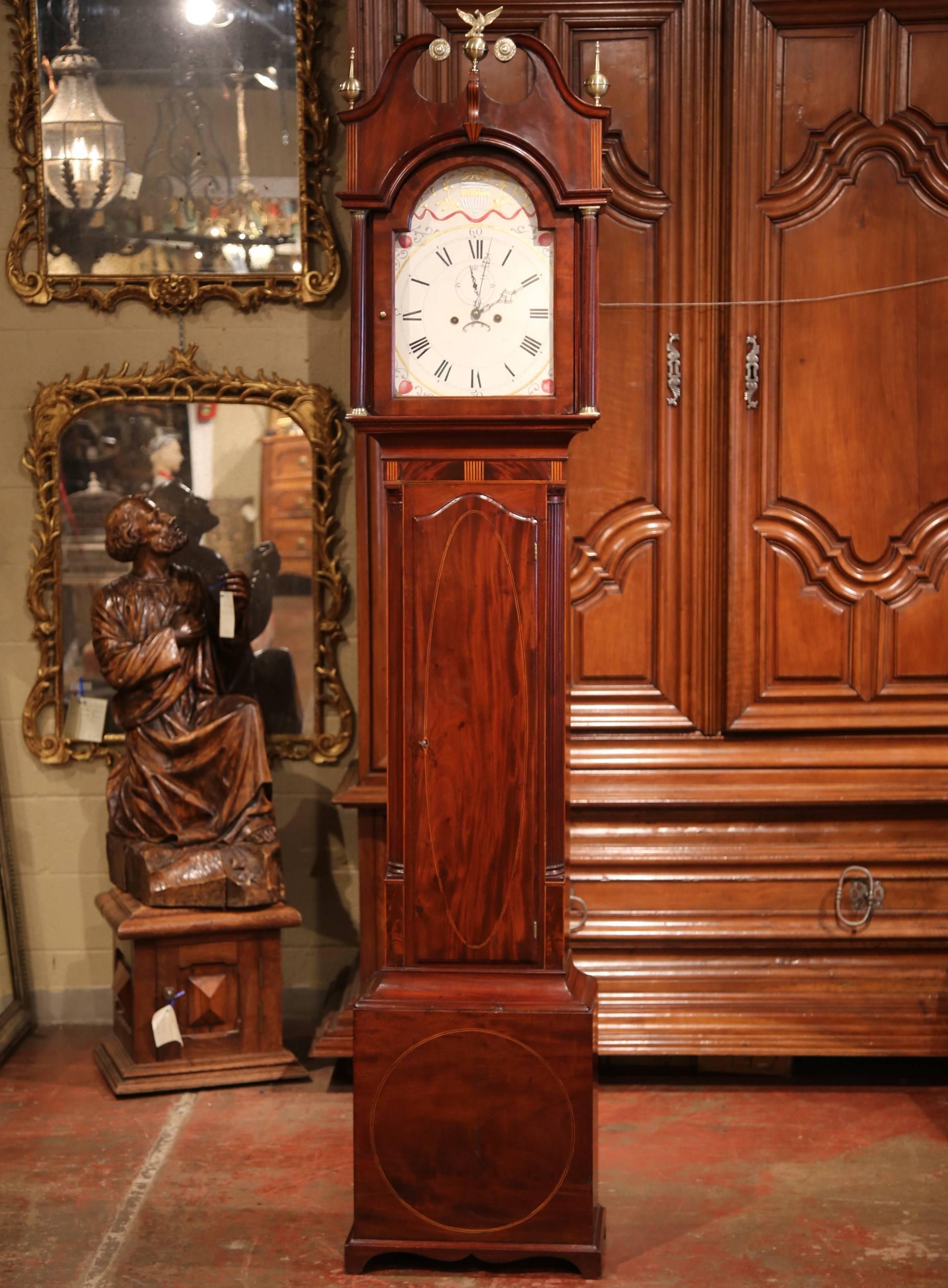 This elegant, antique Chippendale grandfather clock was carved in England, circa 1780. The tall case clock is in very good working order and features brass decorations on top, including a centre eagle and spear finials on both sides. The clock