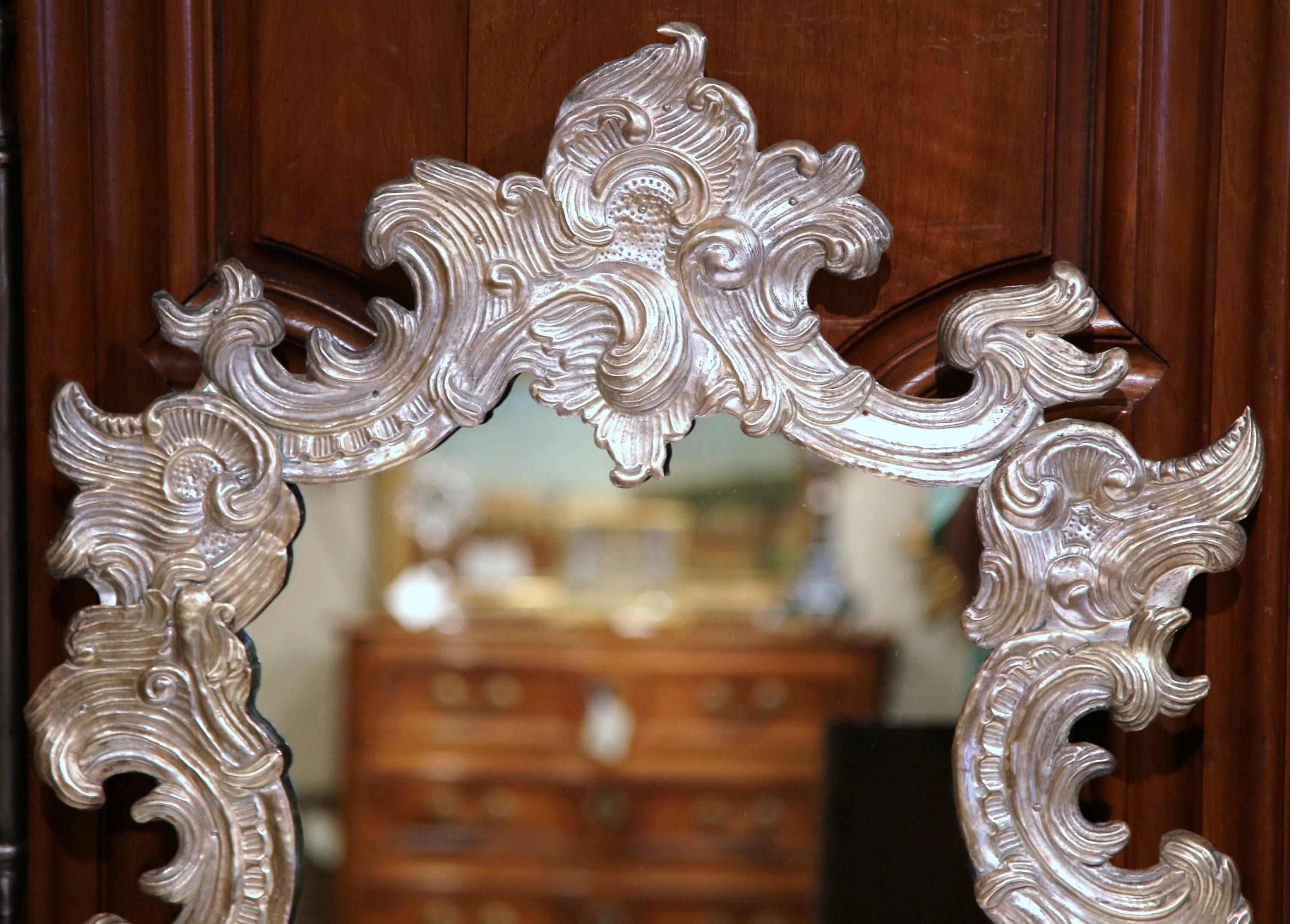 This elegant, antique table mirror was crafted in France circa 1860. The ornate, asymmetrical mirror in the rococo style features intricate copper repousse work with a large shell motif on top. The piece is in excellent condition with rich silver