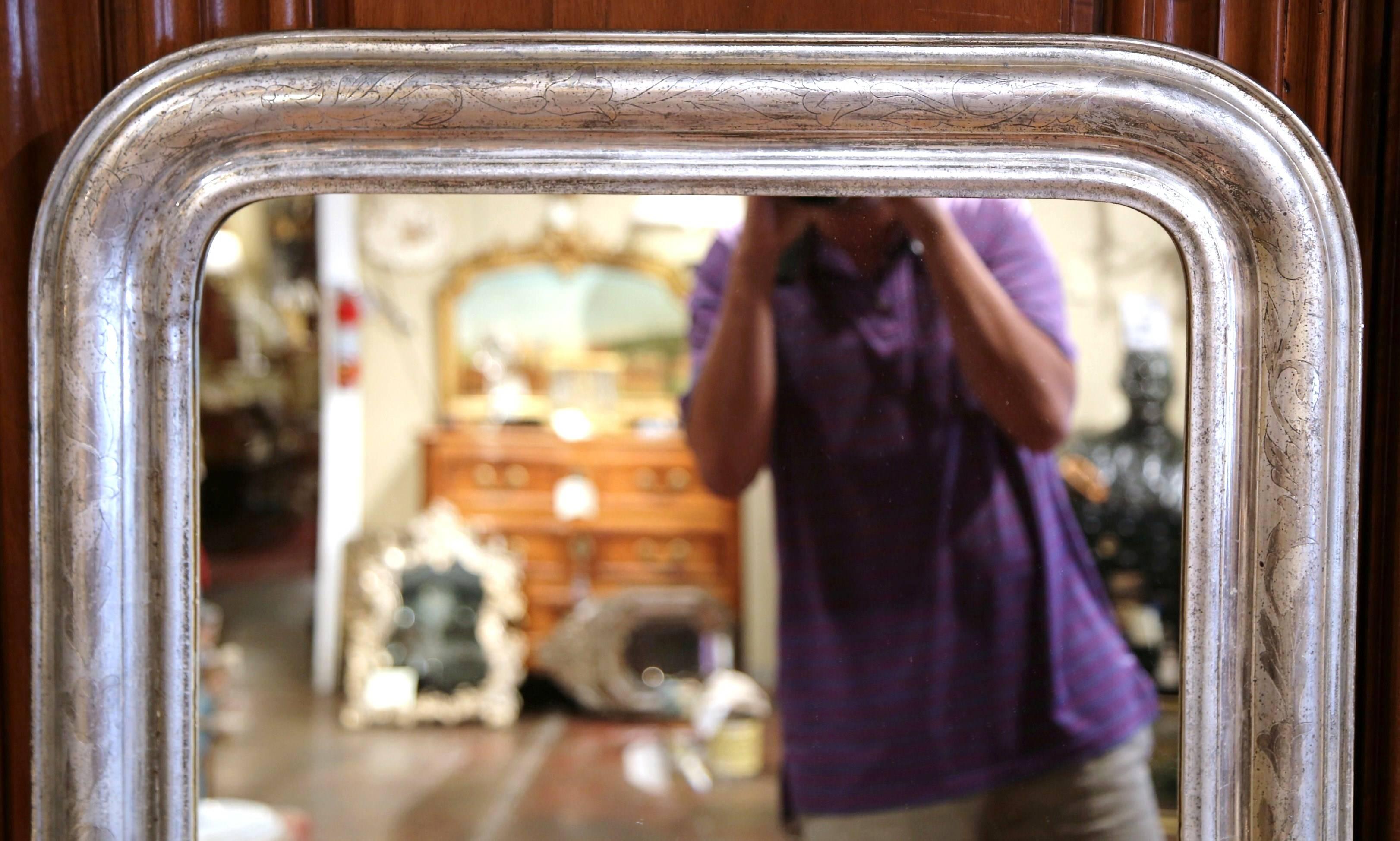 This elegant, antique mirror was crafted in France, circa 1860. The rectangular, wall hanging mirror features some engraved flower decoration around the decorative, silver leaf frame. The piece is in excellent condition with its original rich,