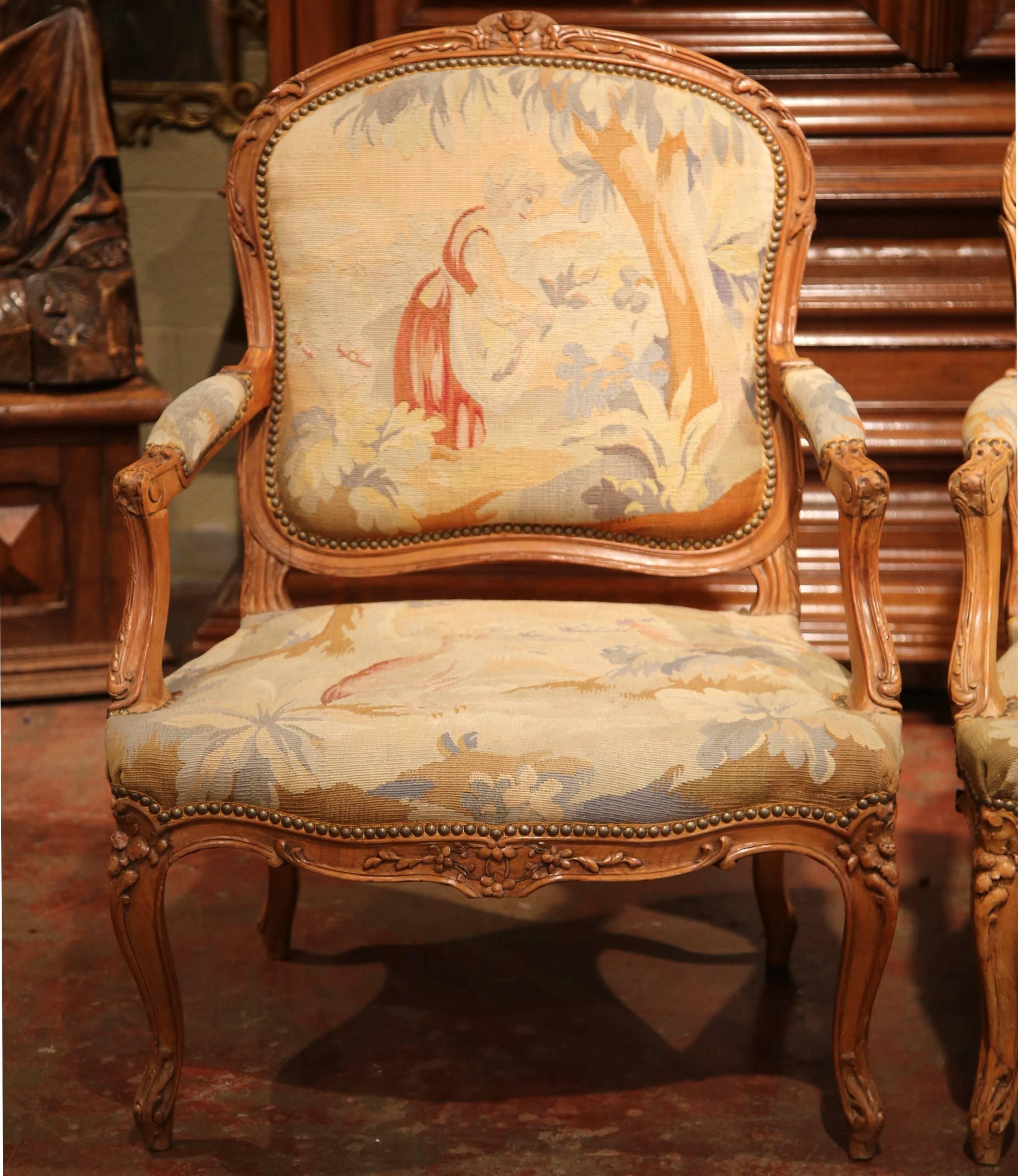 This elegant pair of antique fruitwood armchairs was crafted in Lyon, France circa 1860. Both armchairs are hand-carved and have beautiful cabriole legs and rounded backs. The chairs are both upholstered with original Aubusson tapestry. The scenes