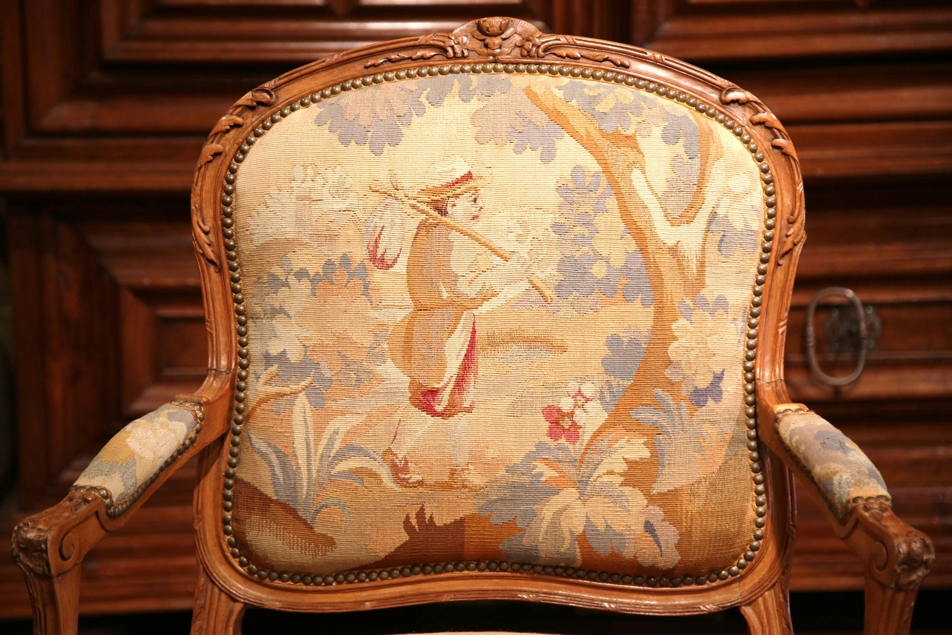 This elegant, antique fruitwood armchair was crafted in Lyon, France circa 1860. The chair has beautiful cabriole legs, carved armrests and a comfortable seat. The chair is upholstered in original Aubusson tapestry in a soft pastel color palette.