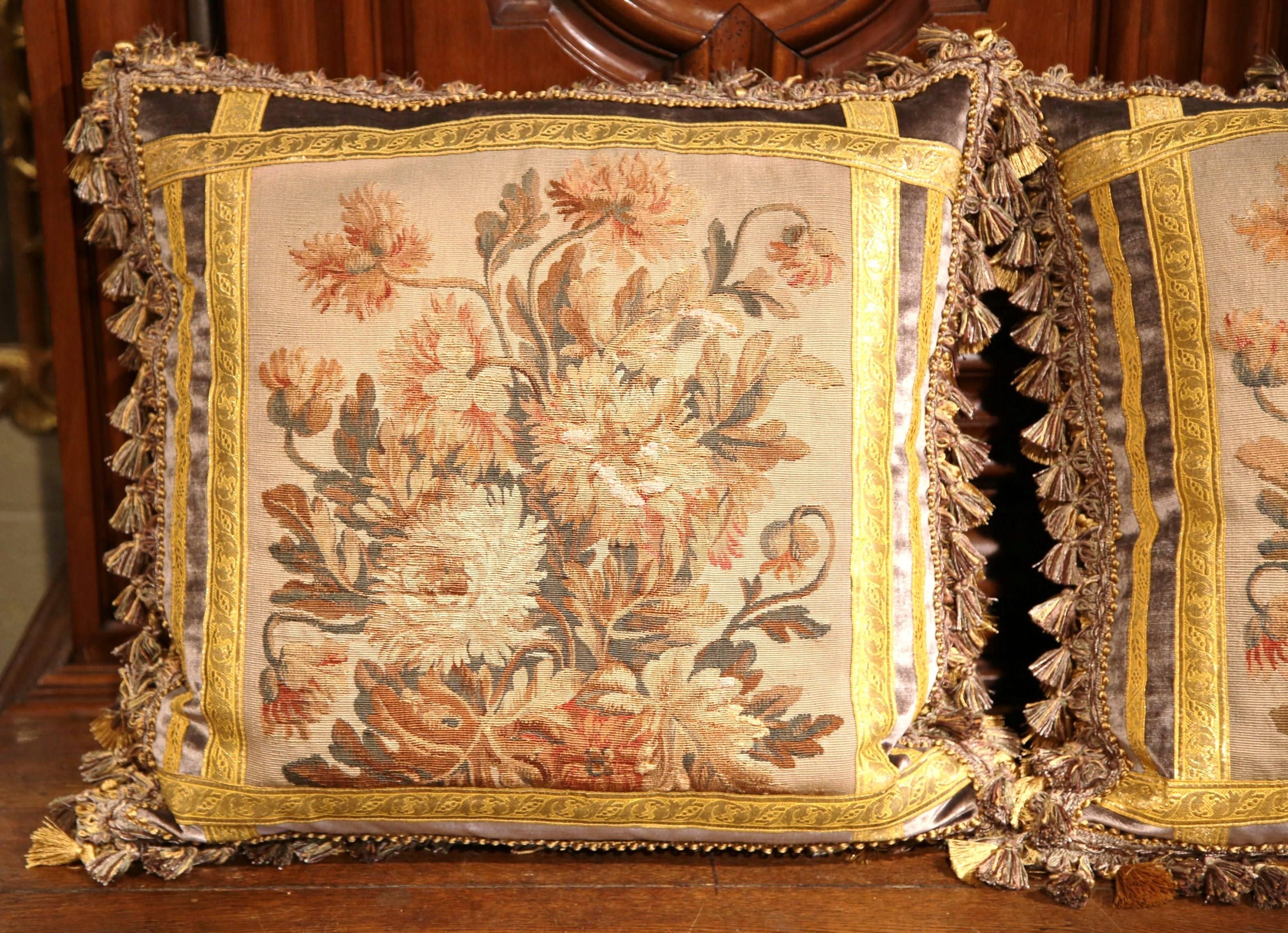 This elegant pair of pillows were crafted using fragments of antique floral tapestry from Aubusson, France. Each of the unique, handmade pillows feature antique, gold trim with complementary tassels and velvet details. The pillows are in excellent