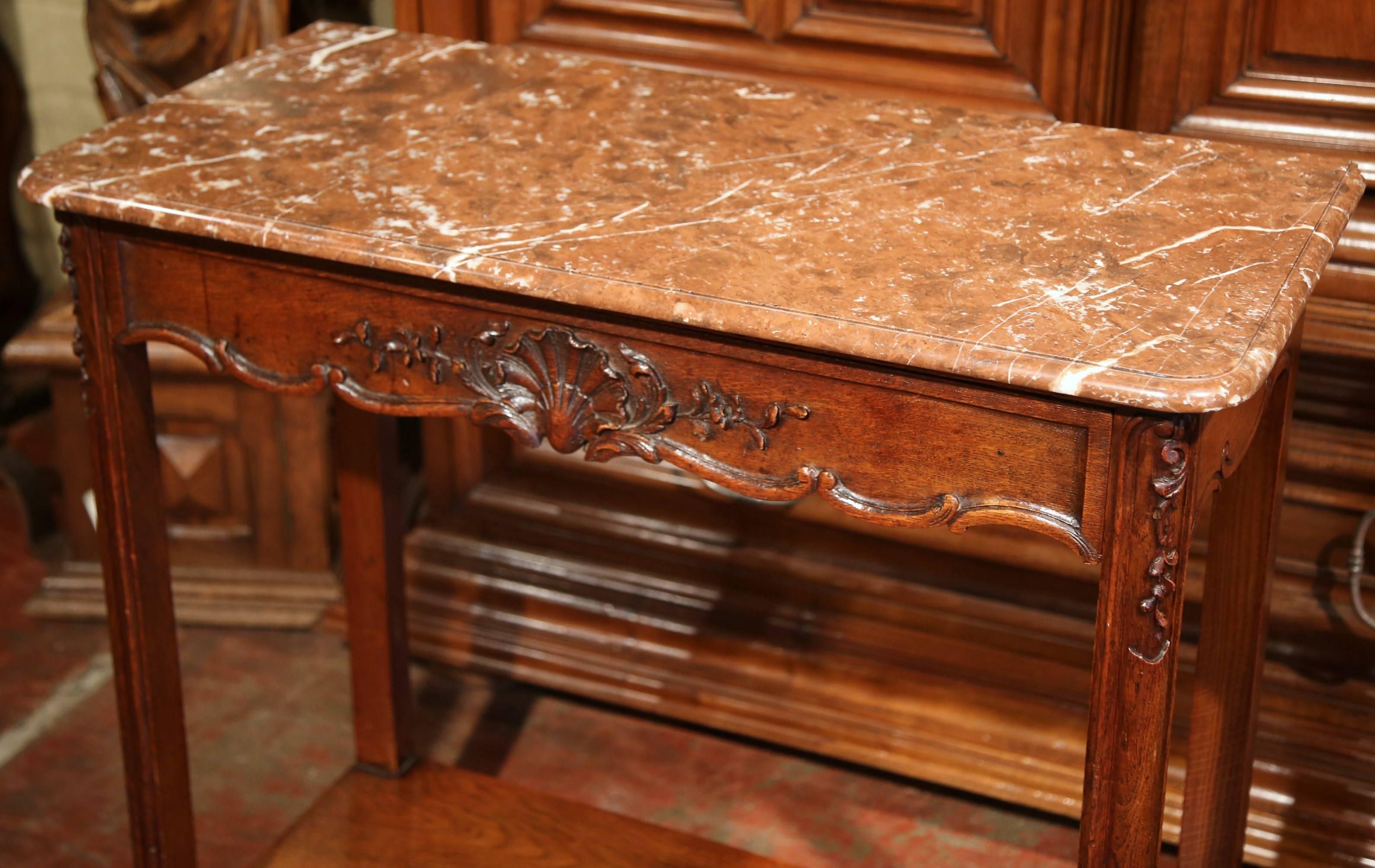 This elegant, antique console was crafted in Normandy, France, circa 1890. The tall, four-leg side table has a beautiful red marble top and a long single drawer across the front decorated with a carved shell. Underneath there's a bottom shelf for
