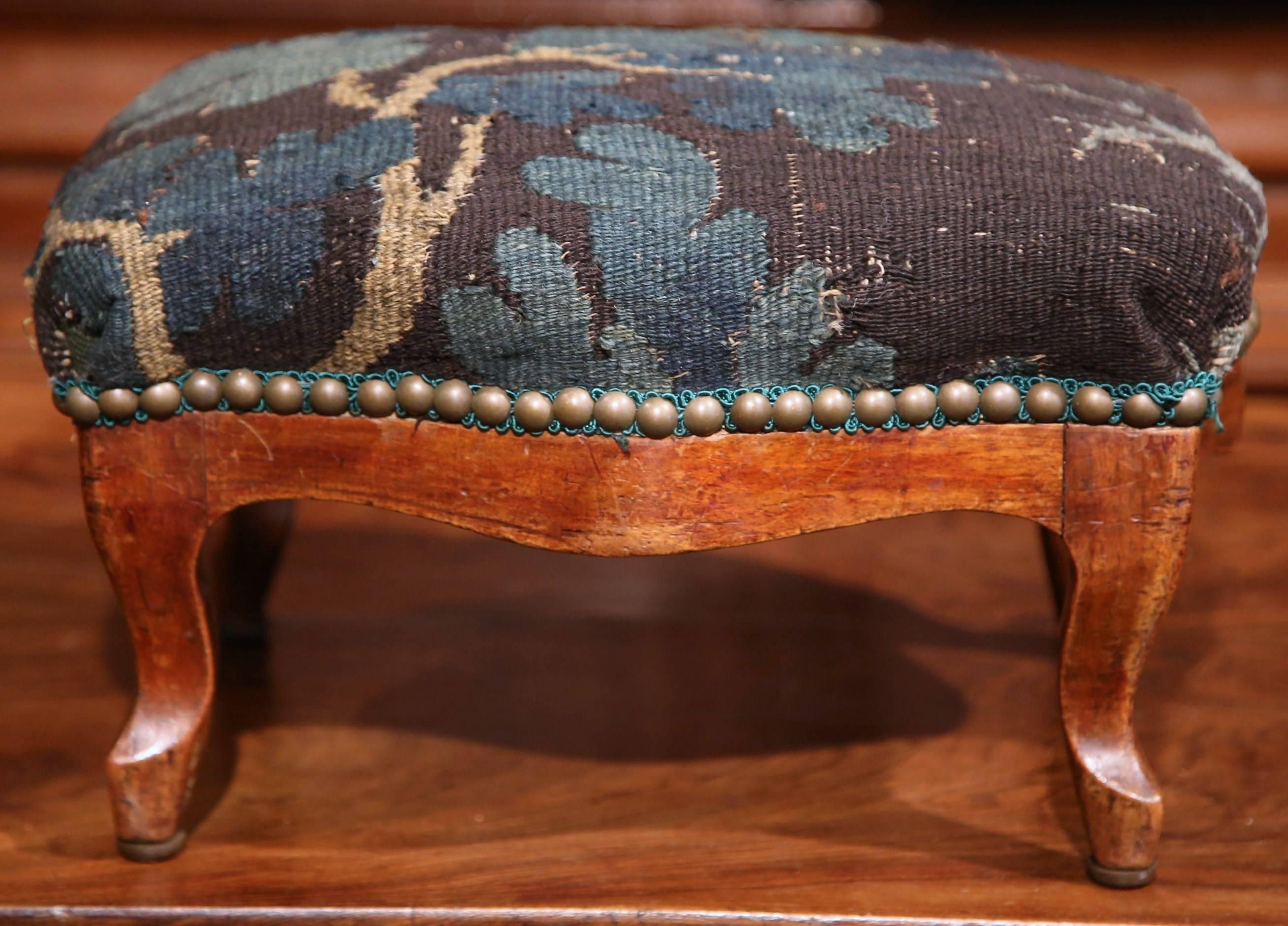 This elegant, antique footstool was crafted in Lyon, France, circa 1860. The carved, square footrest has been reupholstered with old Aubusson fragment in a soft blue and green palette. The piece is in excellent condition with a rich walnut patina