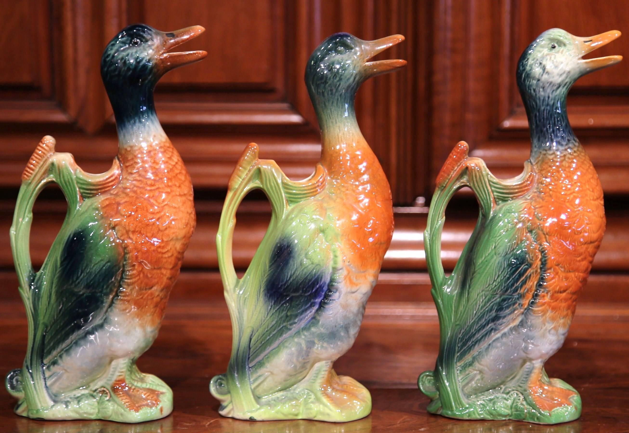 This beautiful set of Majolica water pitchers were sculpted in France, circa 1910. Each hand painted, ceramic jug is in the shape of a colorful duck, and has an open beak as a spout and a back handle for easy pouring. Two of the porcelain bird