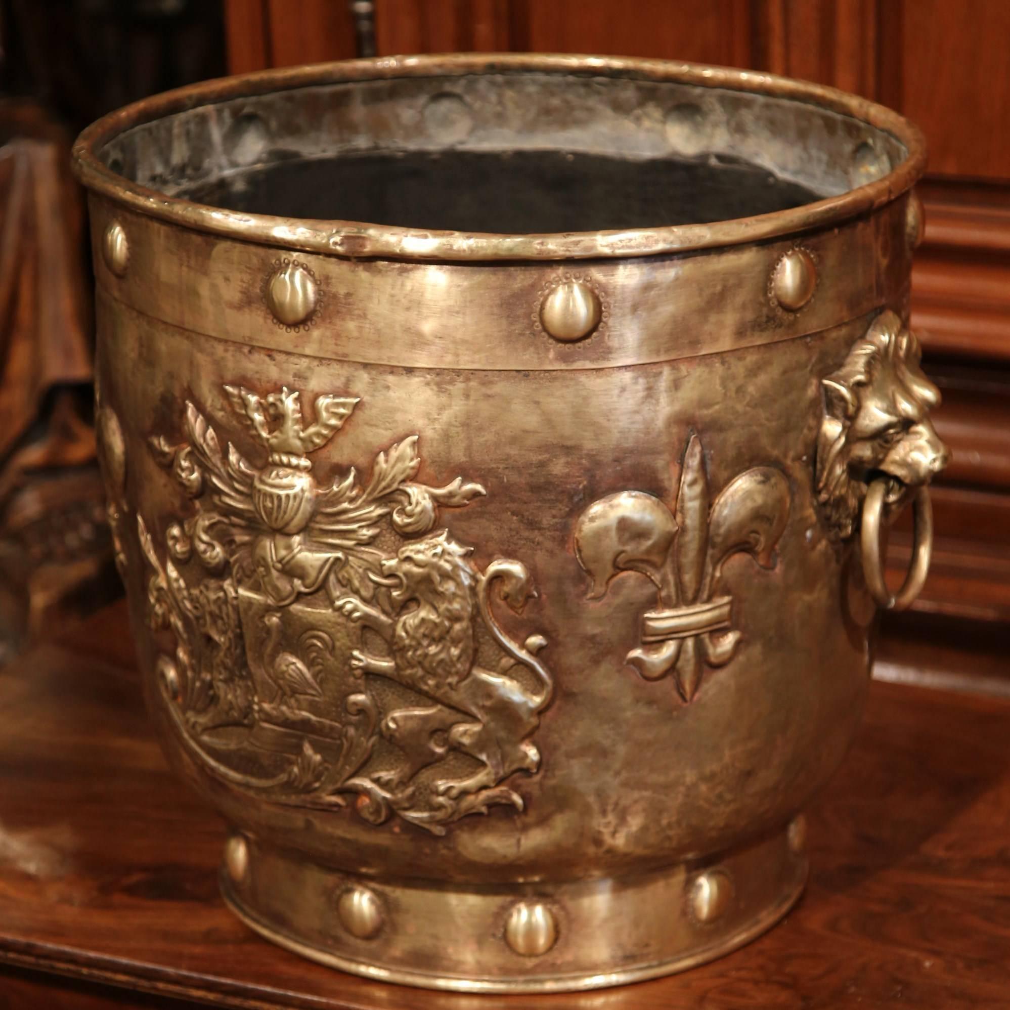 This large, antique jardiniere was crafted in Southern France, circa 1870. The brass planter has two lion head handles, and repousse relief decor around the sides. The motifs include Classic themes such as fleur-de-lys, coat of arms and fruit