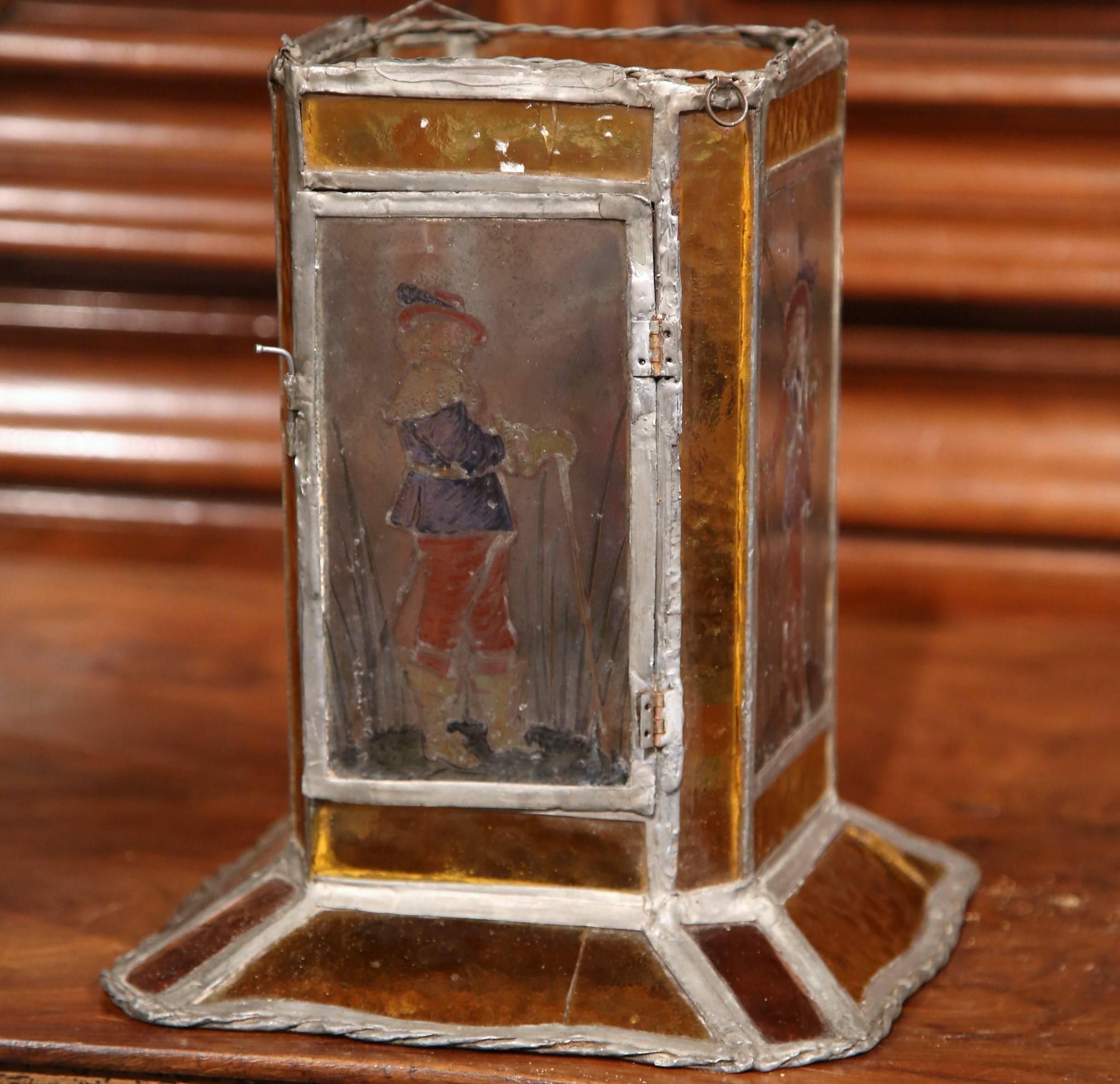 This interesting stain glass table lantern was created in Southern France, circa 1820. The small, unique lantern features four musketeers in courtly attire. The fixture has a small door on one side so you can place a candle inside. The light is in