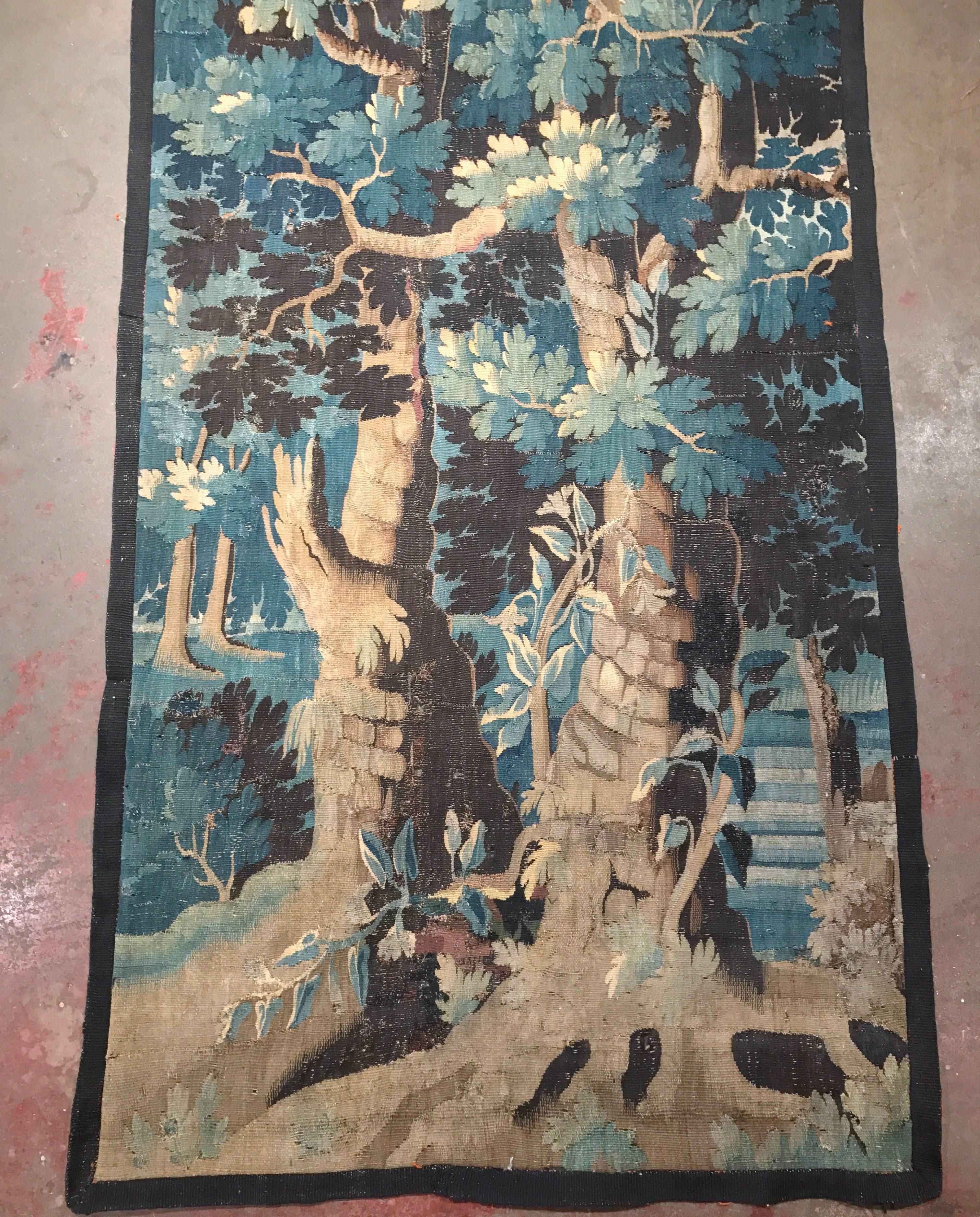 This long, narrow tapestry was woven in Aubusson, France, circa 1750. The colorful, antique, verdure wall hanging features two trees with leaves in a lush, verdant, blue, green and beige palette. The piece is in good condition with wear commensurate