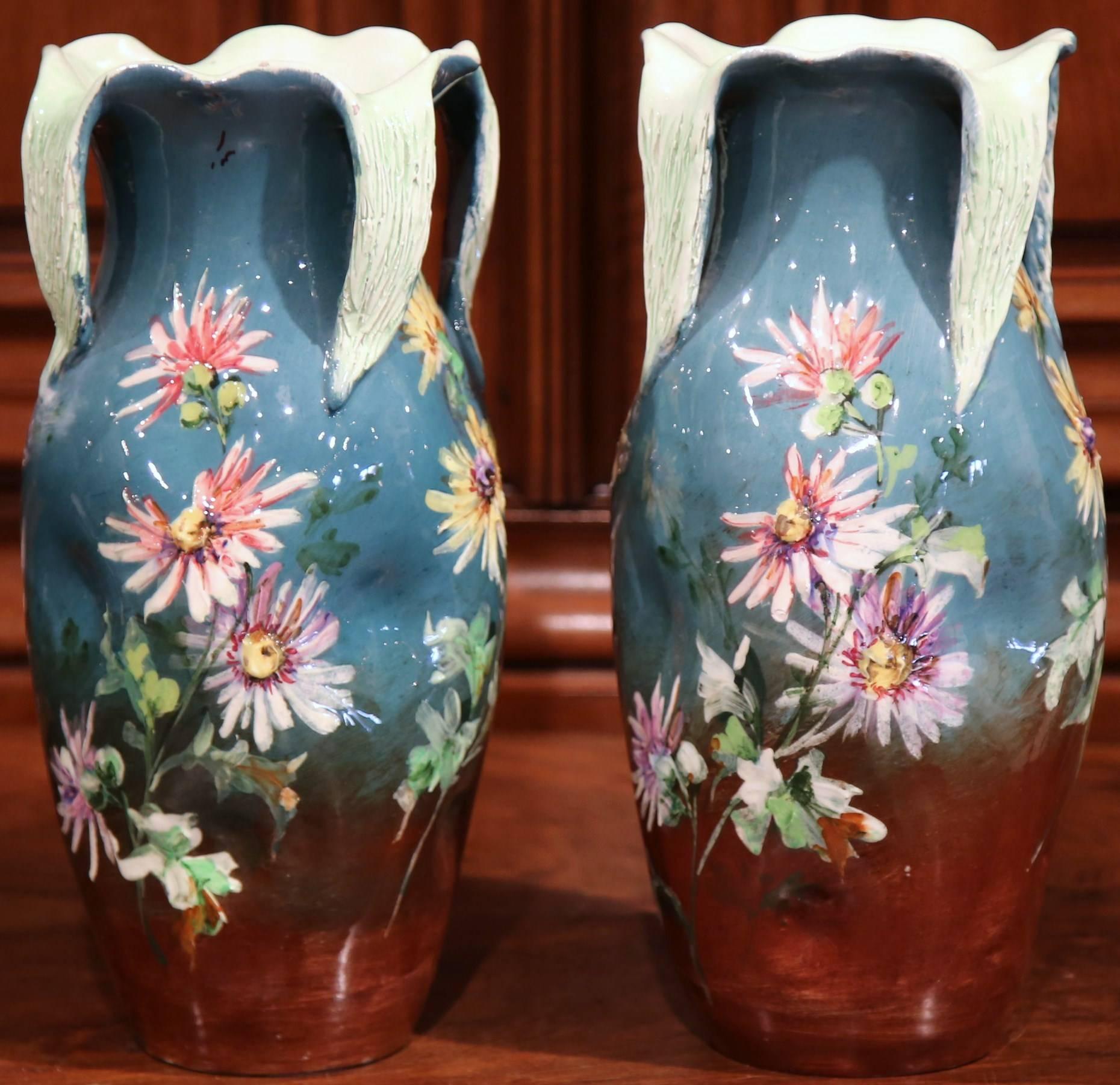 Place these tall and colorful antique Majolica vases on a mantel or a console. Sculpted in Vallauris, France, circa 1880, these ceramic vases feature hand painted daisies in the pink and yellow palette, embellished with four green curled back leaves
