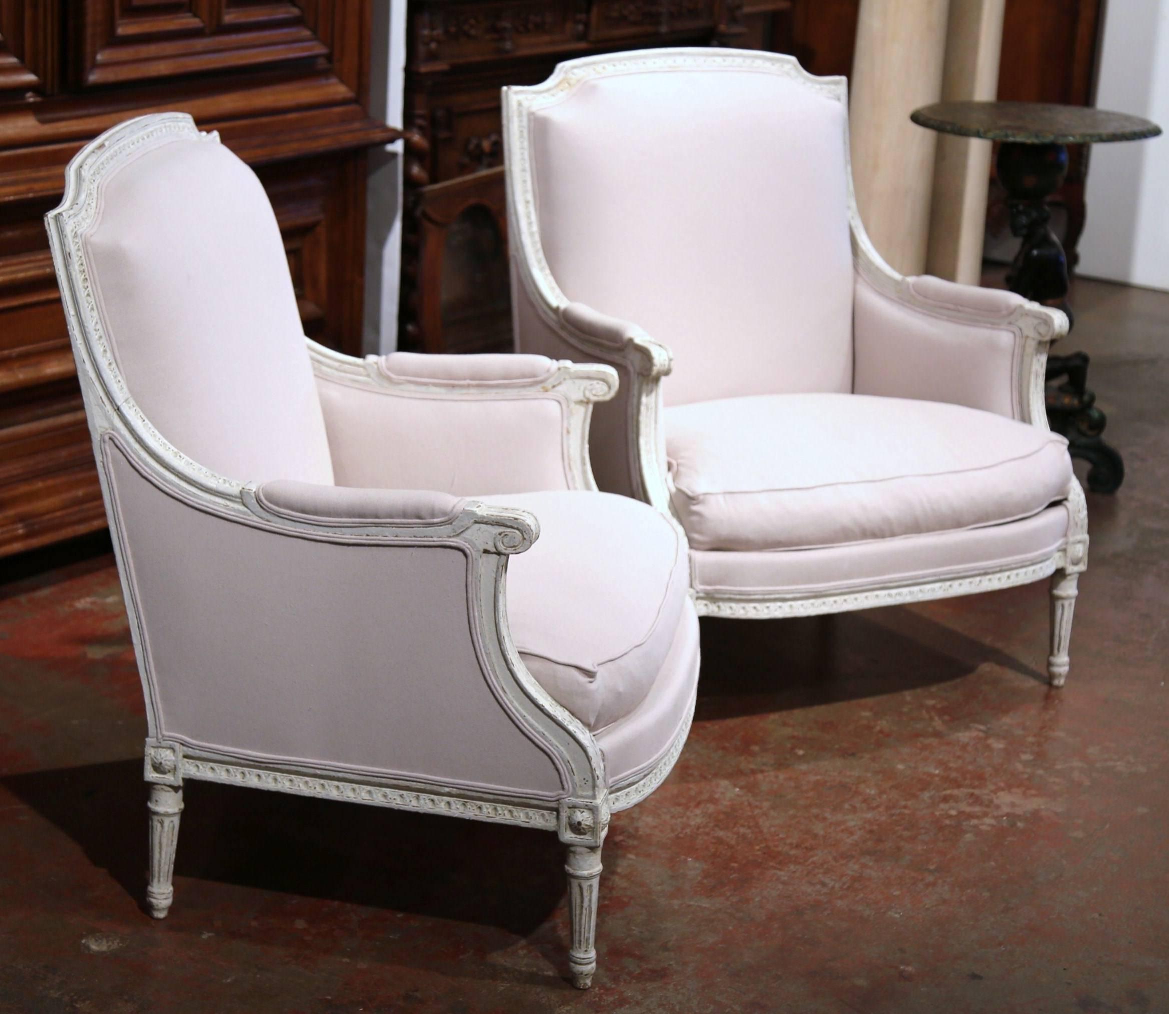 This elegant pair of antique armchairs was created in France circa 1870. The large armchairs feature a carved frame, tapered legs with square medallions, armrests on both sides and comfortable, plush down seat cushions. Both chairs are upholstered