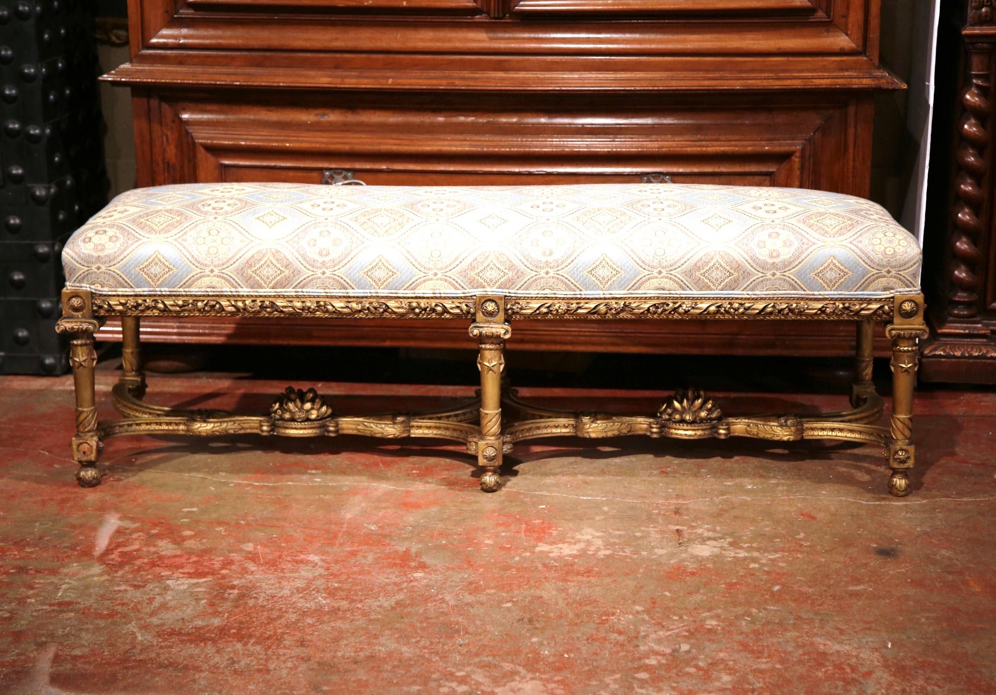 Place this elegant antique bench at the foot of your king-size bed! Crafted in France, circa 1810, the bench with six legs features a carved apron around the frame and a very ornate stretcher with a center flower vase. The bench springs has been