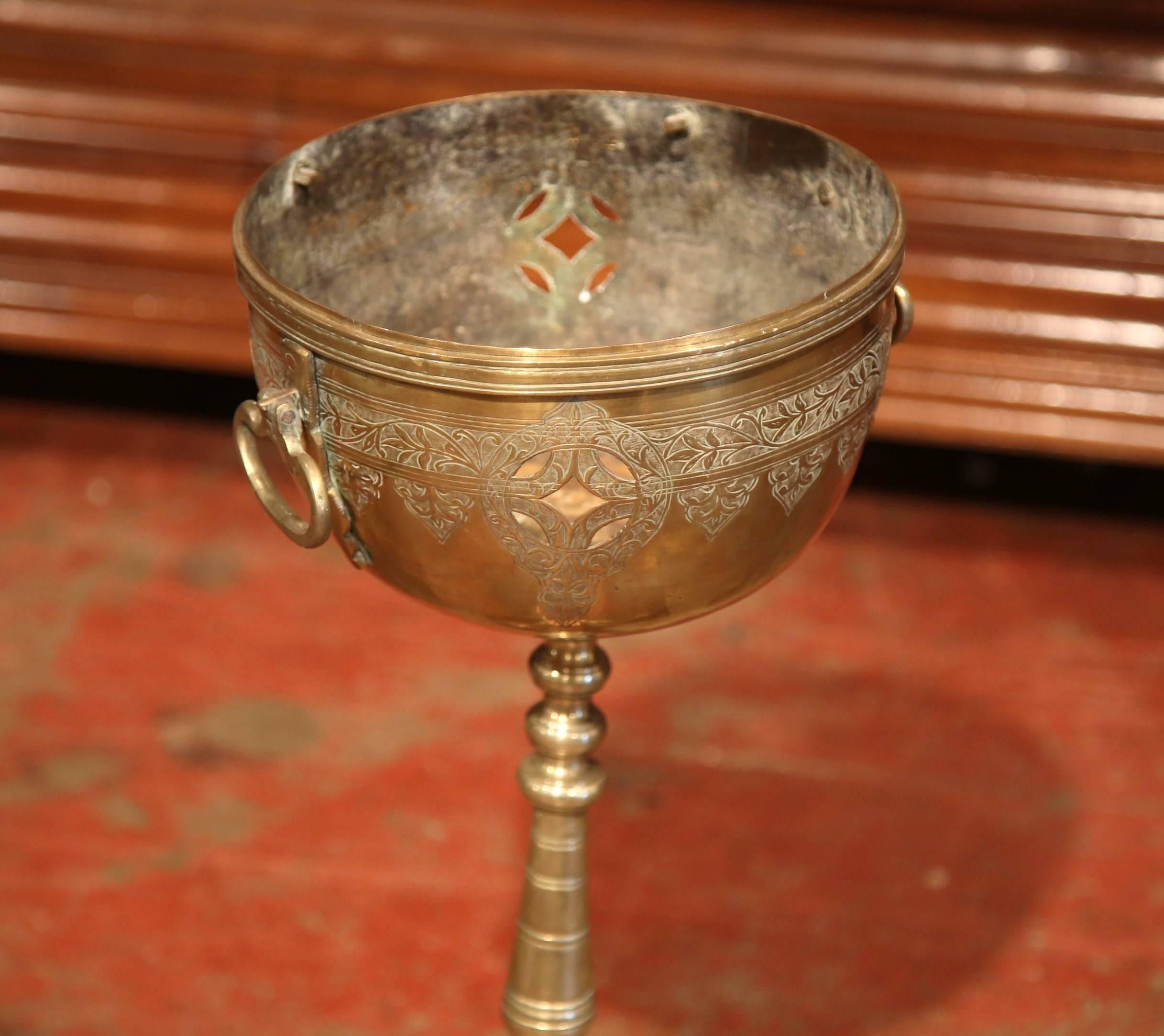 This interesting, antique planter was crafted in France, circa 1870. The bronze and brass planter features engraved decorative foliage and fleur-de-lys on the elevated round bowl and a pair of side handles. The turned pedestal has three legs with